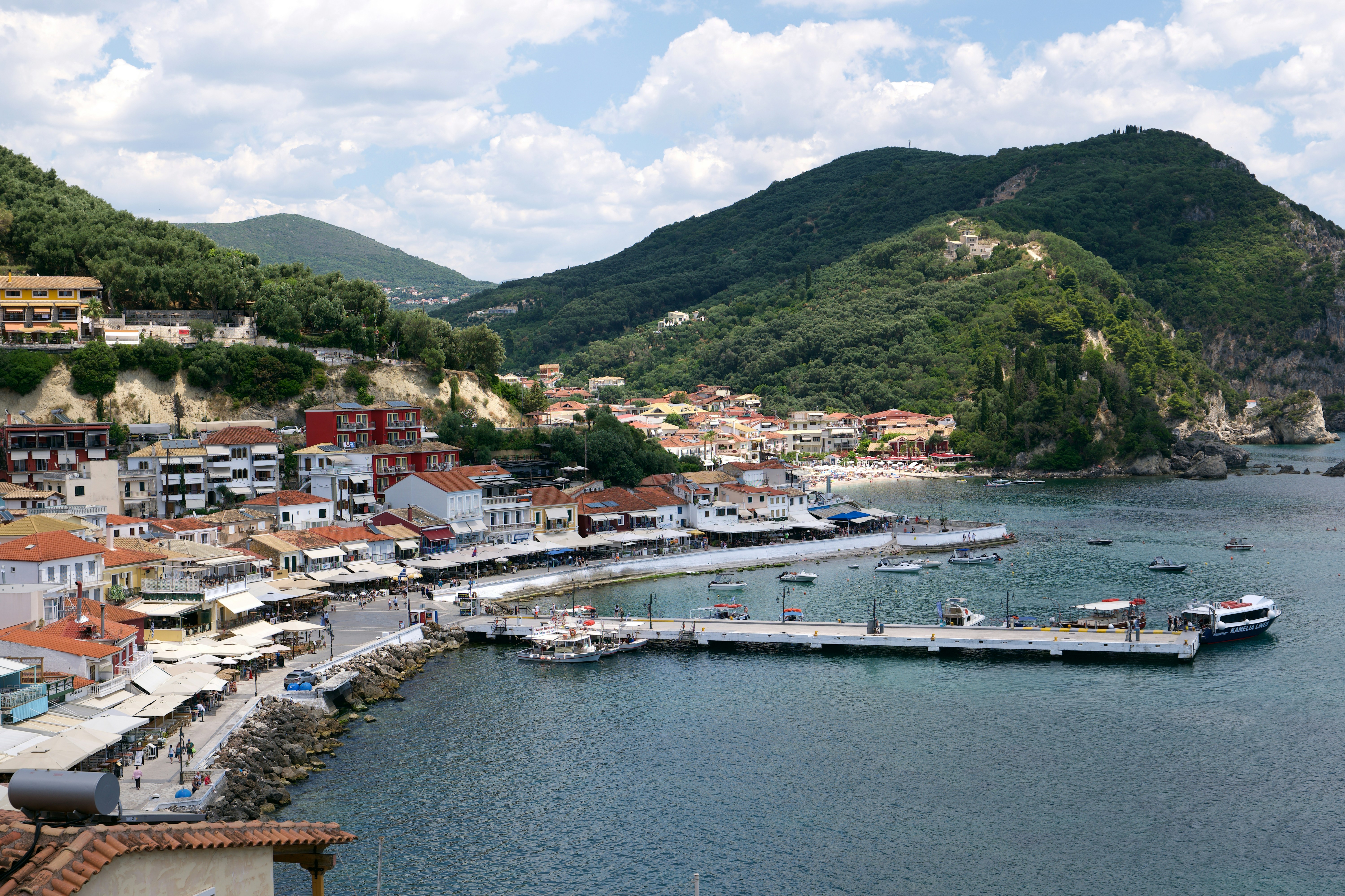 A coastal town with red-roofed buildings along a harbor in Parga, Greece