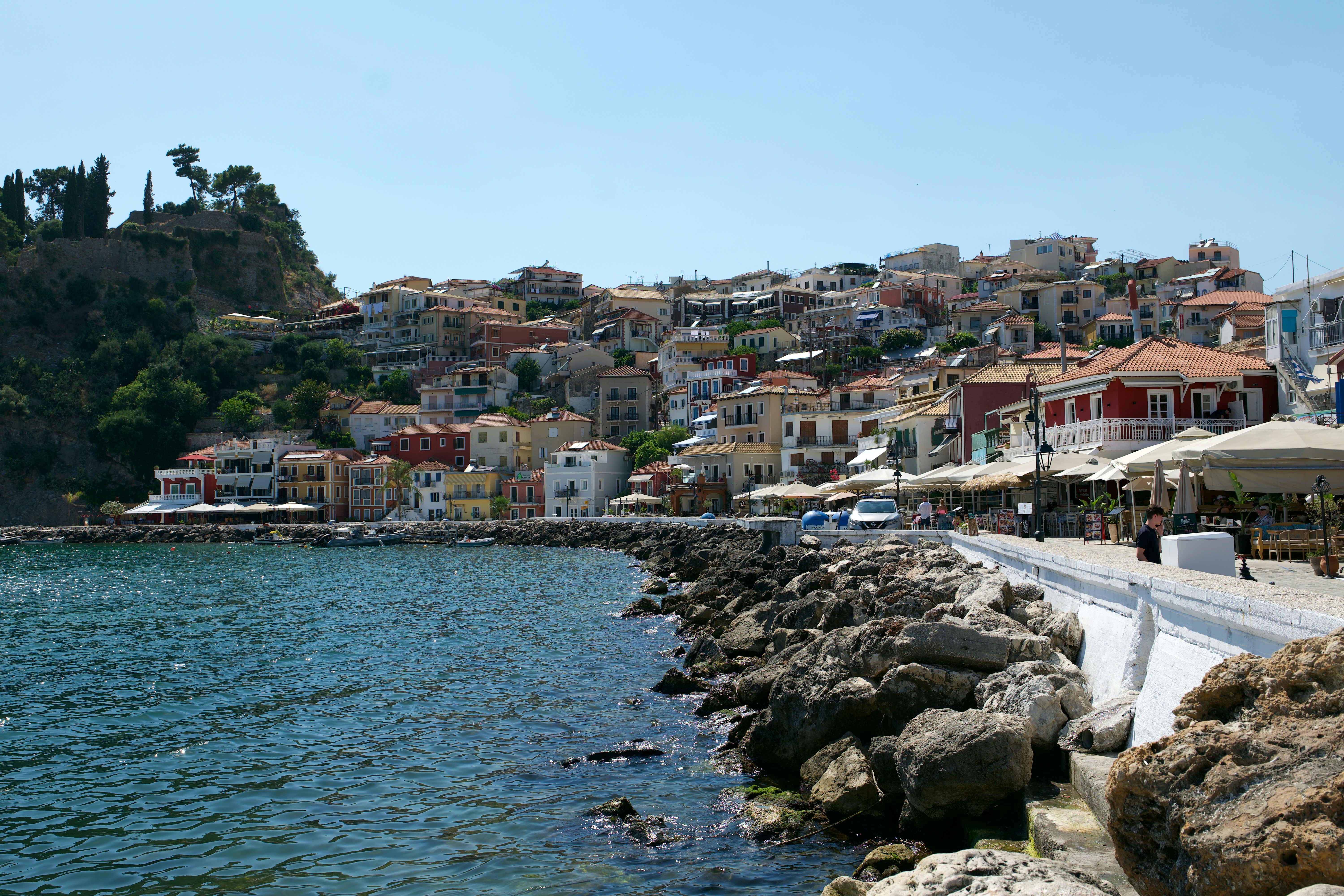 A coastal town with colorful houses on a hillside overlooking a rocky harbor