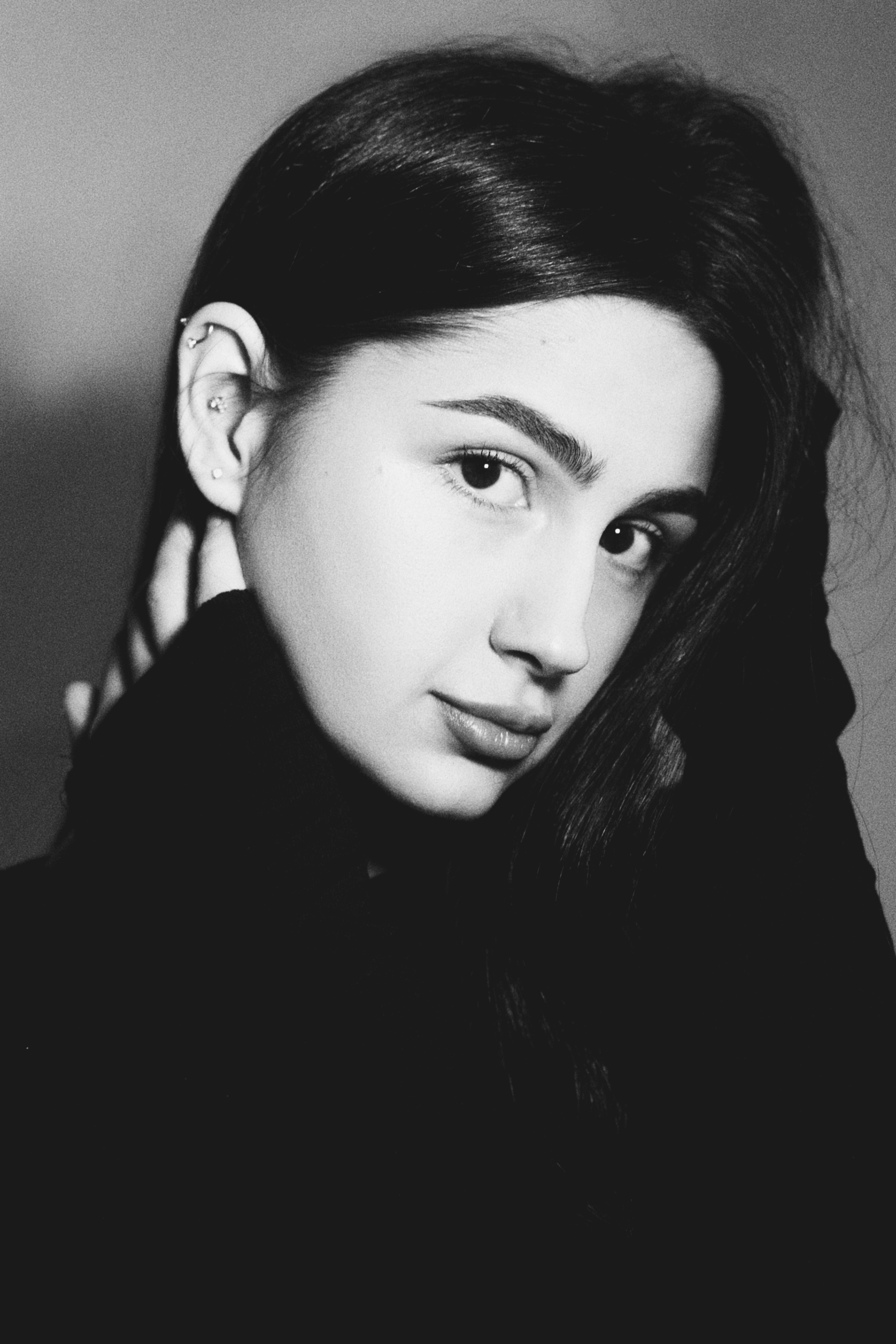 A woman with dark hair and multiple ear piercings in a black sweater