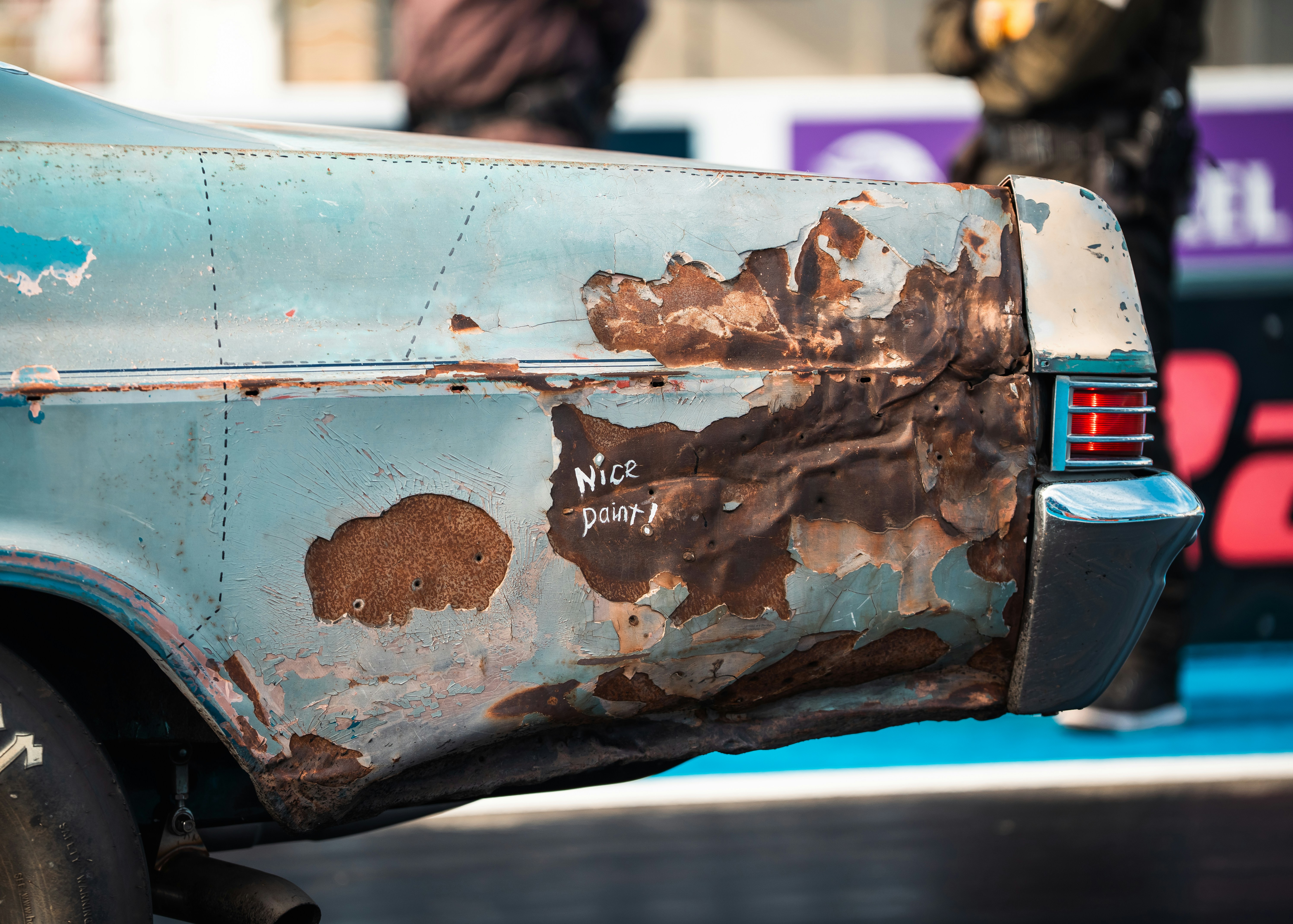 Blue vehicle body panel with rust and peeling paint.