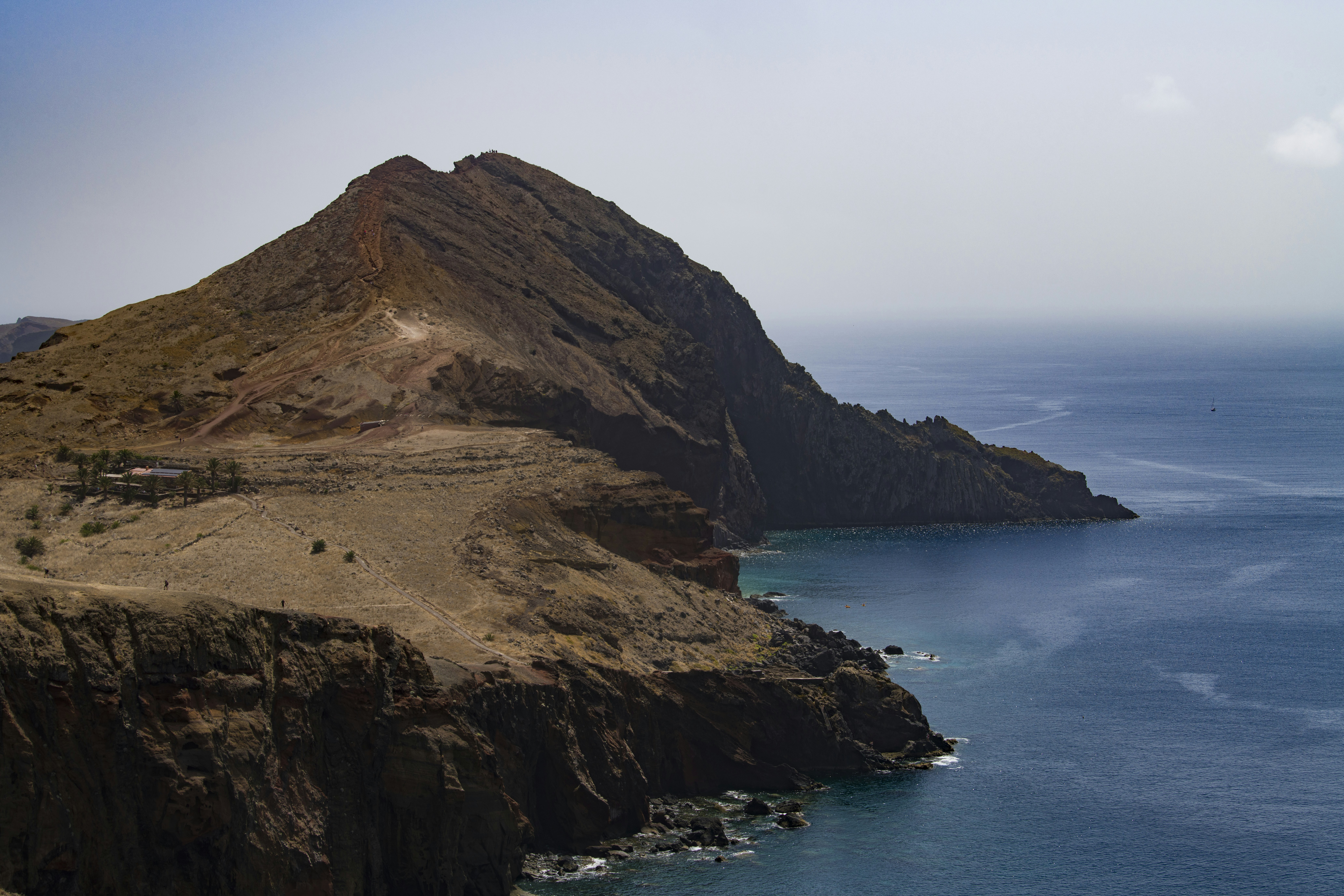 A rocky coastal cliff rising above the deep blue Atlantic Ocean