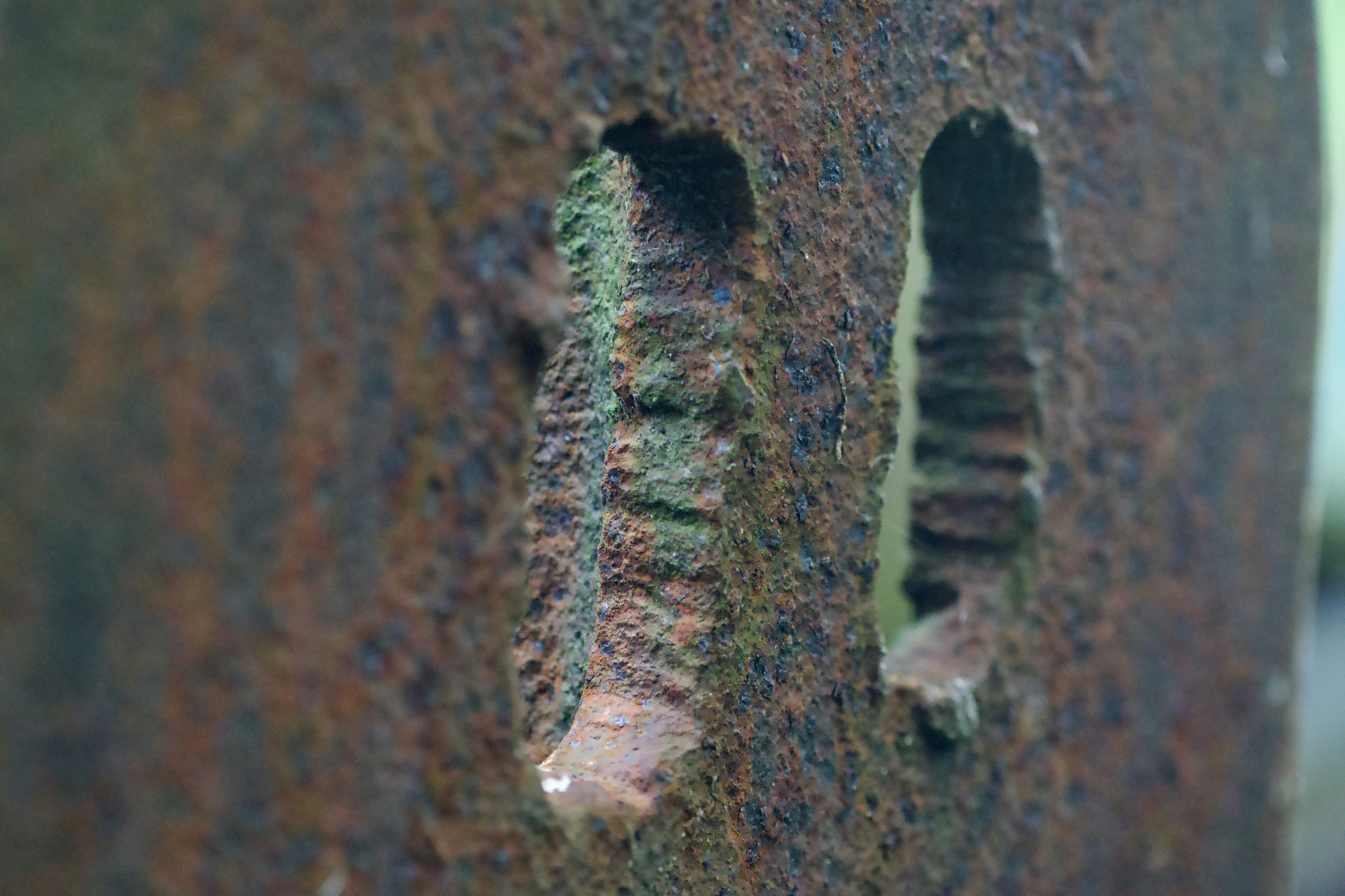 Two vertical slots in a weathered piece of rusted brown metal
