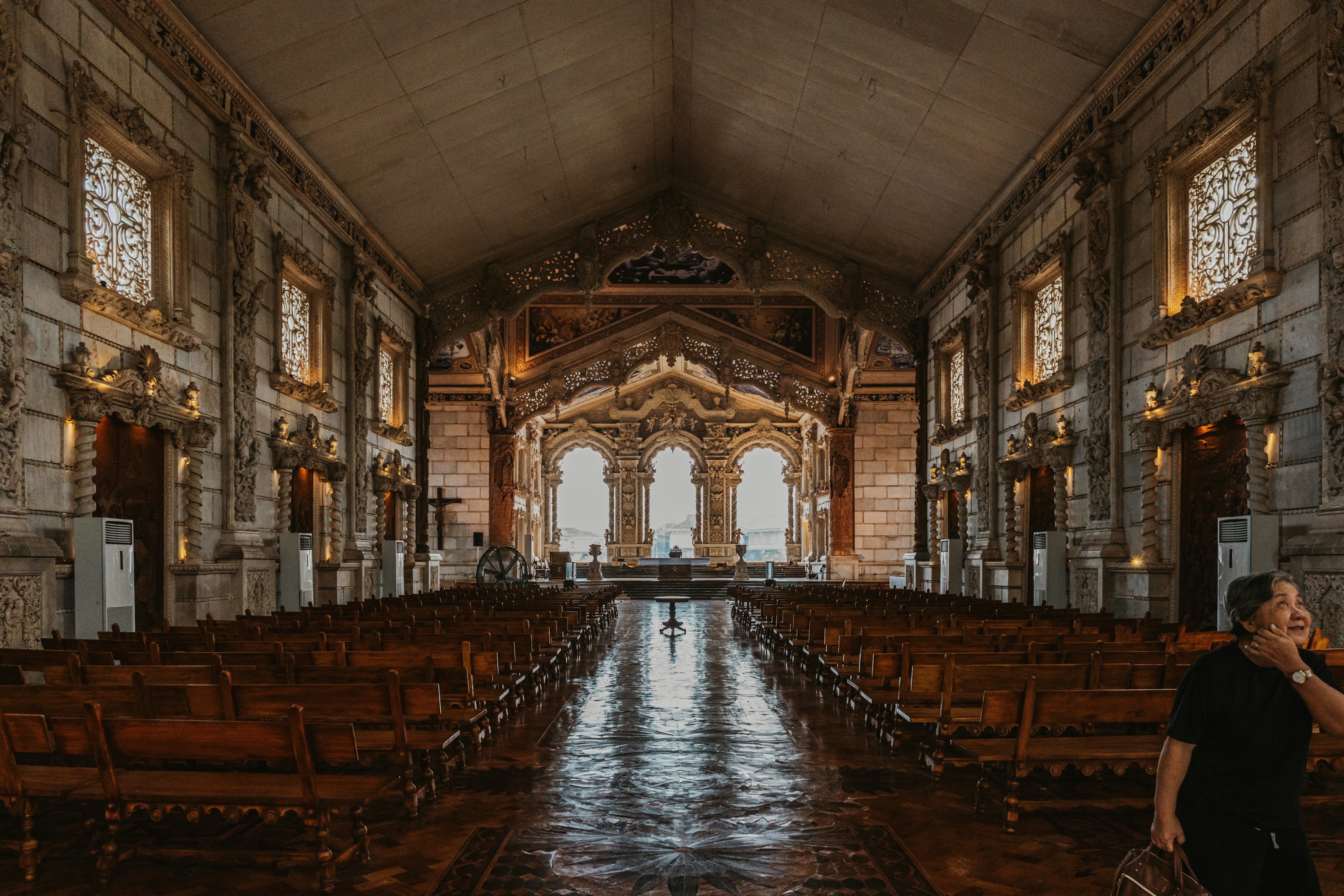 An older woman in a black shirt inside a grand ornate church interior