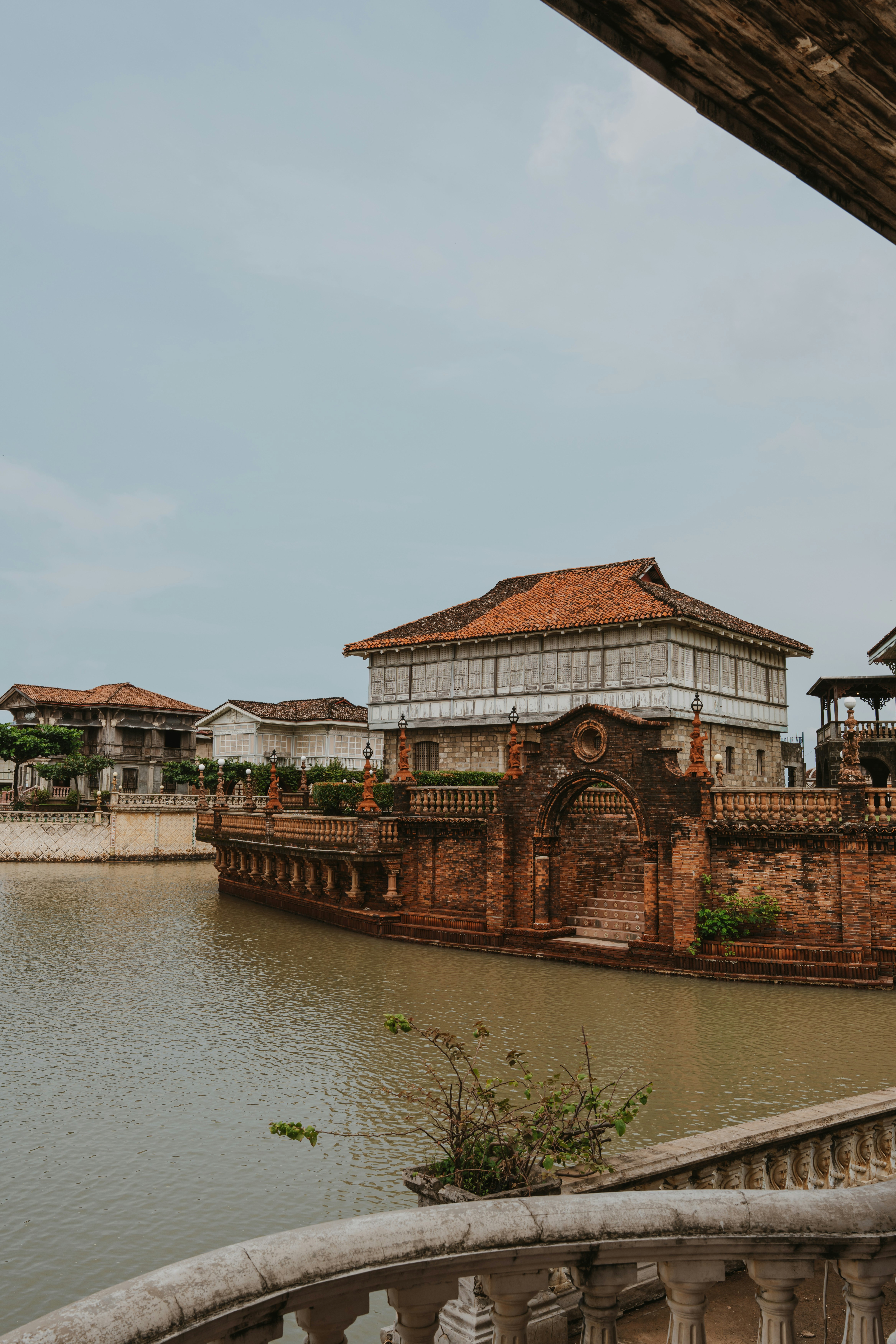 Traditional colonial architecture with tiled roofs along a calm water canal under an overcast sky