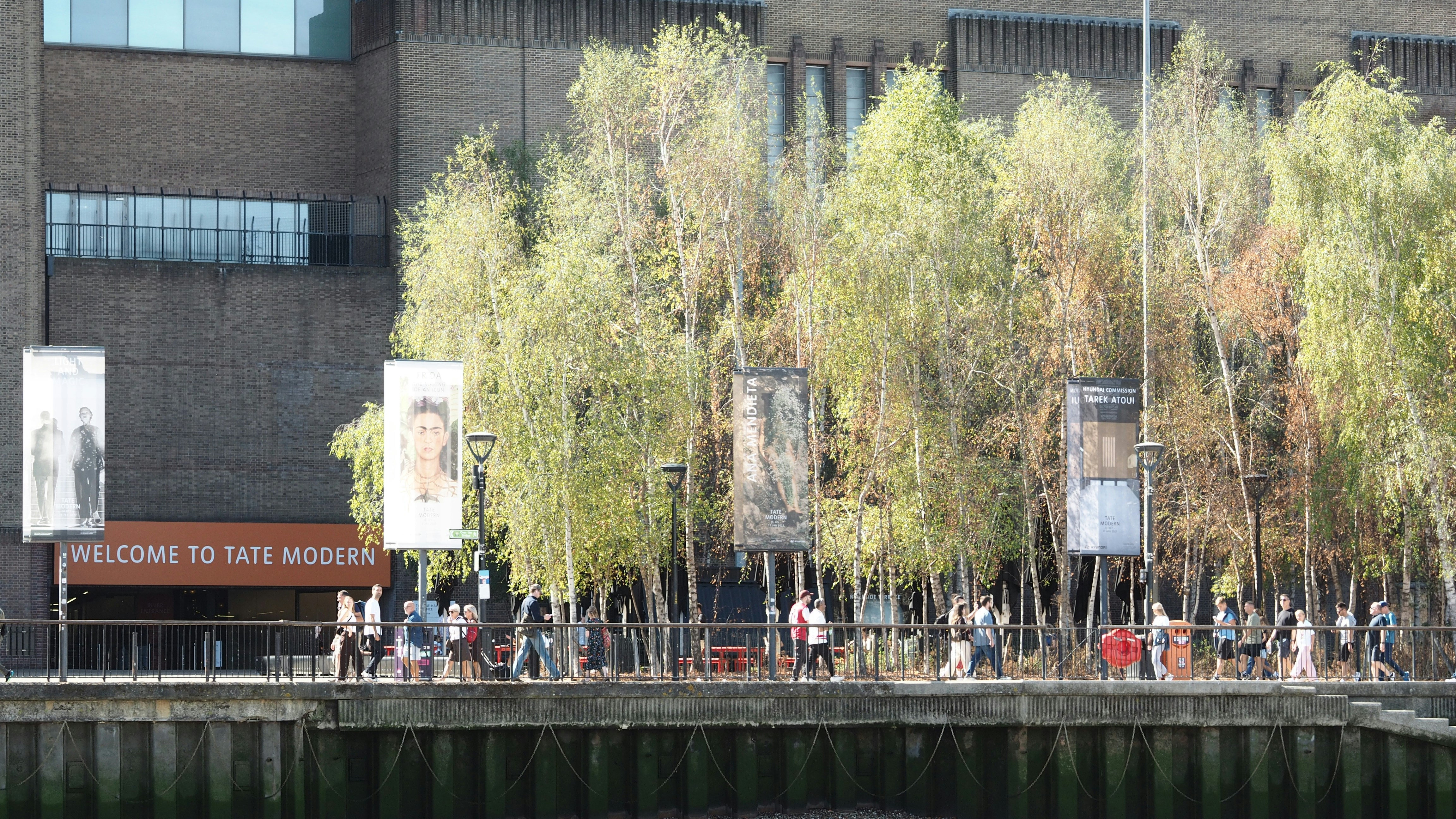 People walking along a riverside path by the Tate Modern in London