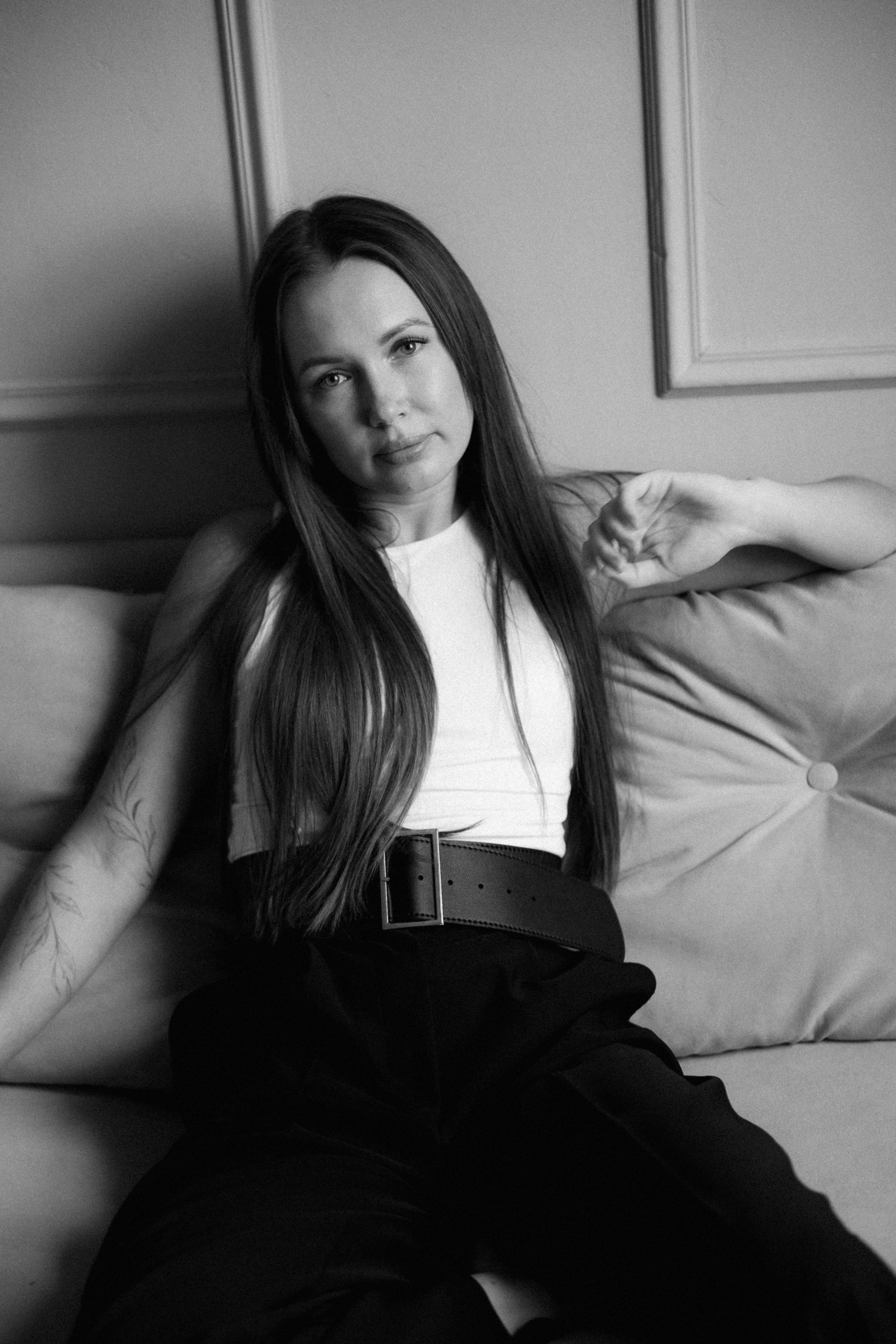 A woman with long hair and a floral arm tattoo on a sofa