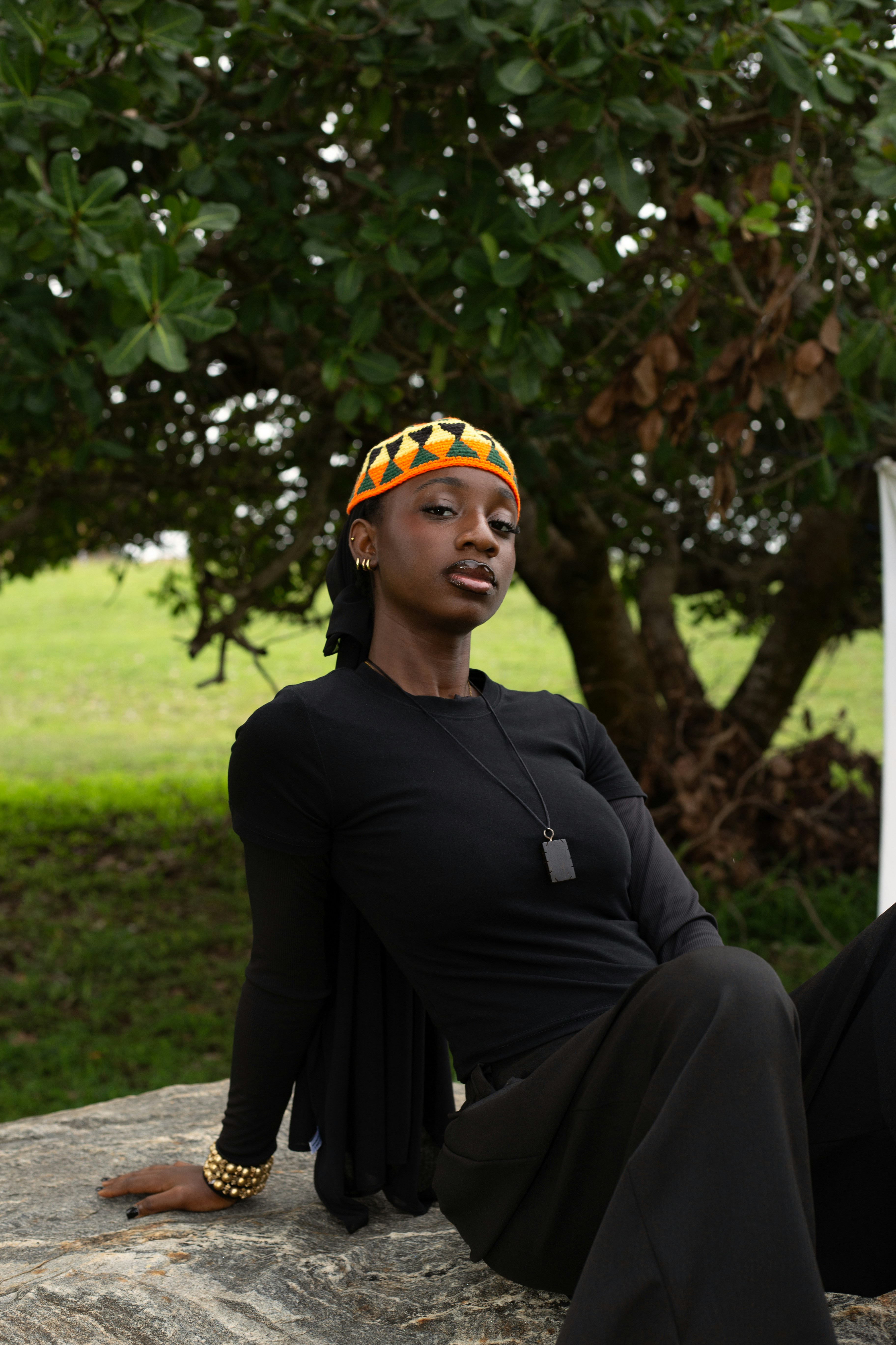 A woman in a black long-sleeved shirt and patterned cap sitting on a rock
