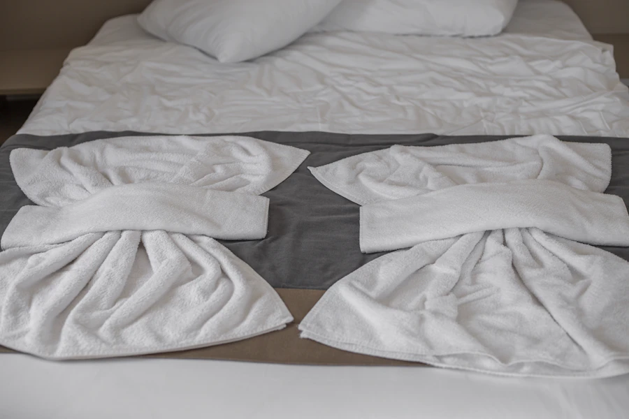 Deux serviettes blanches pliées sur un lit fait