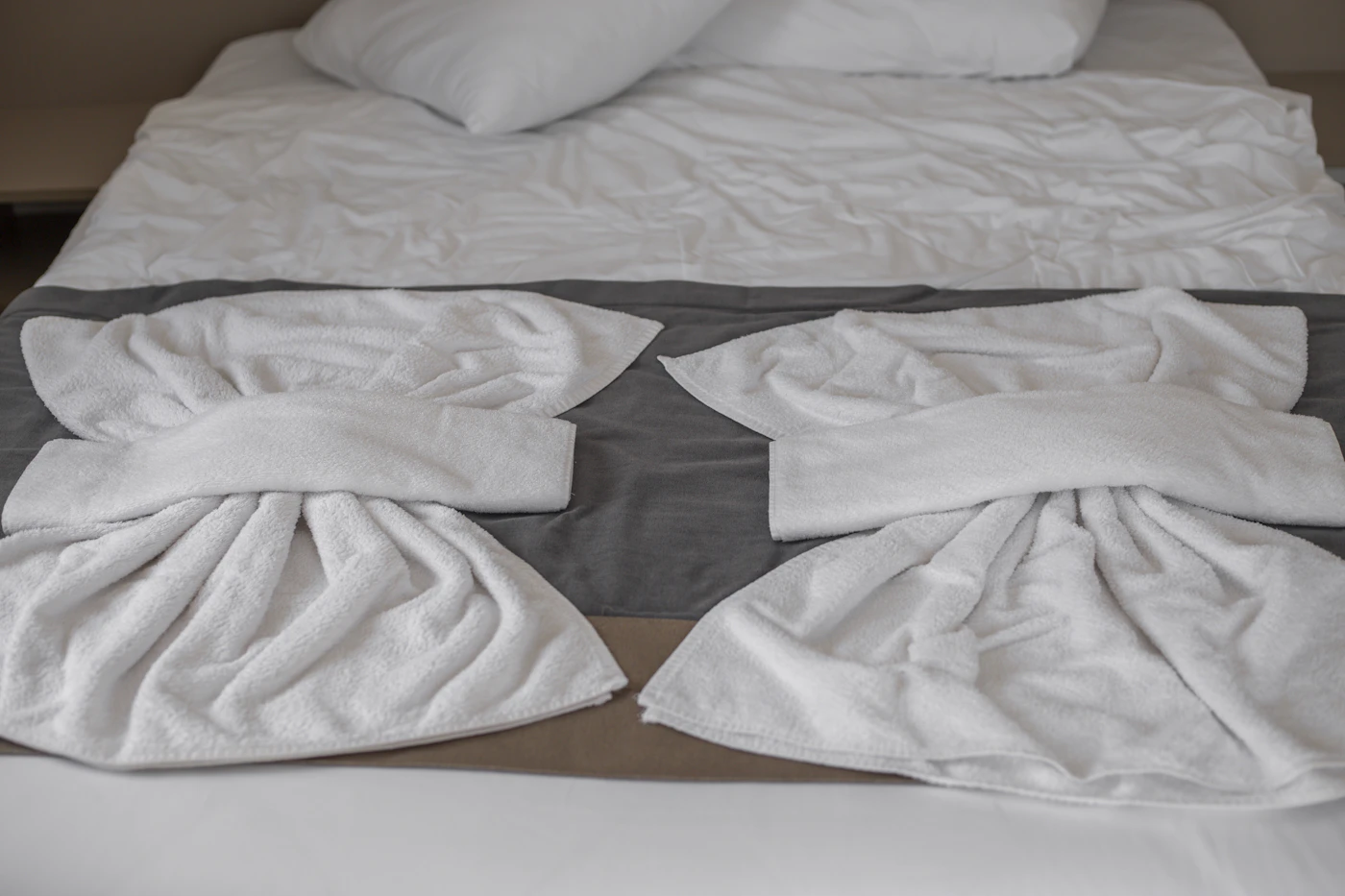 Freshly folded white towels on a made bed