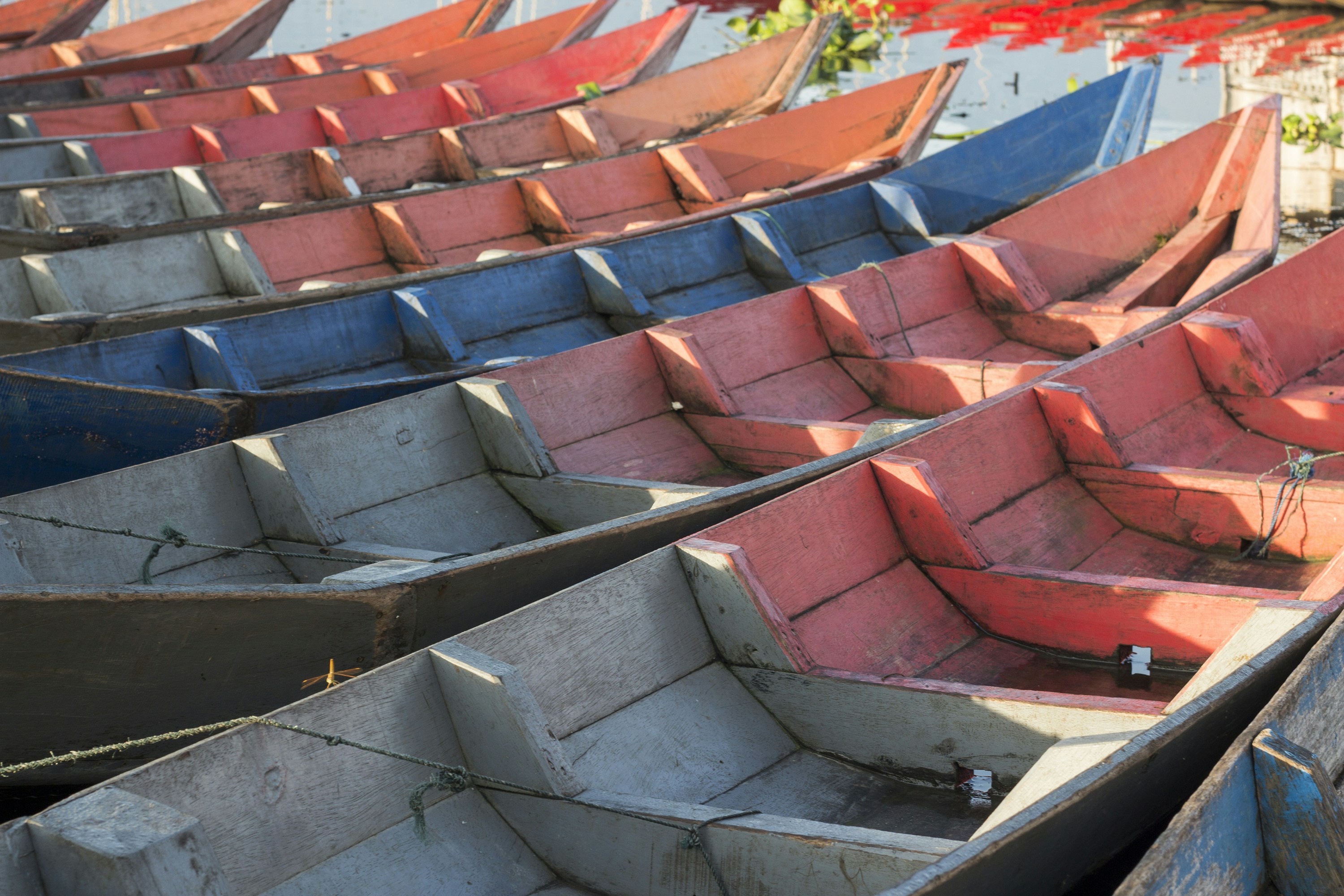 A row of colorful wooden boats moored together on calm water