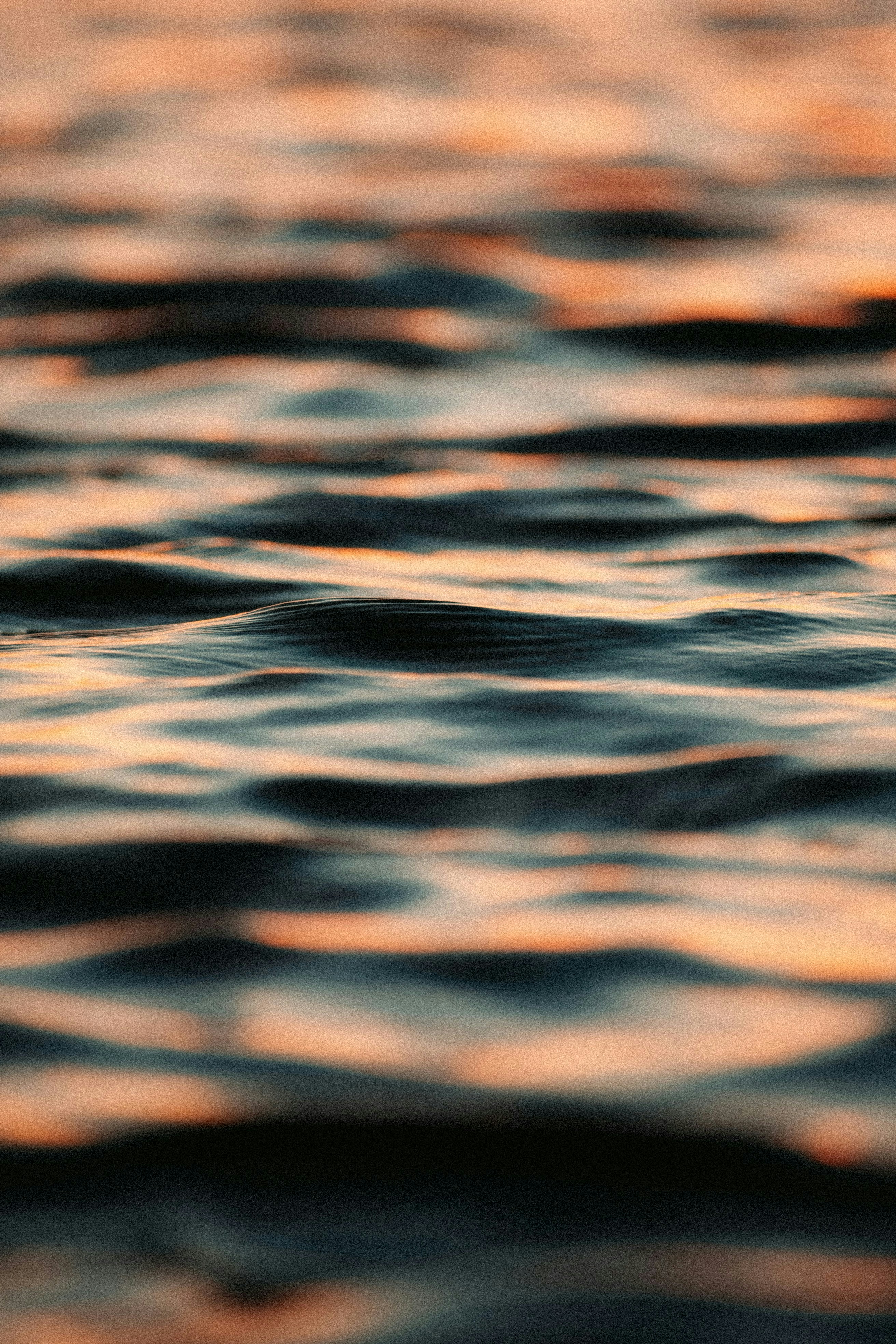 Dark water ripples reflecting warm orange light from a low sun