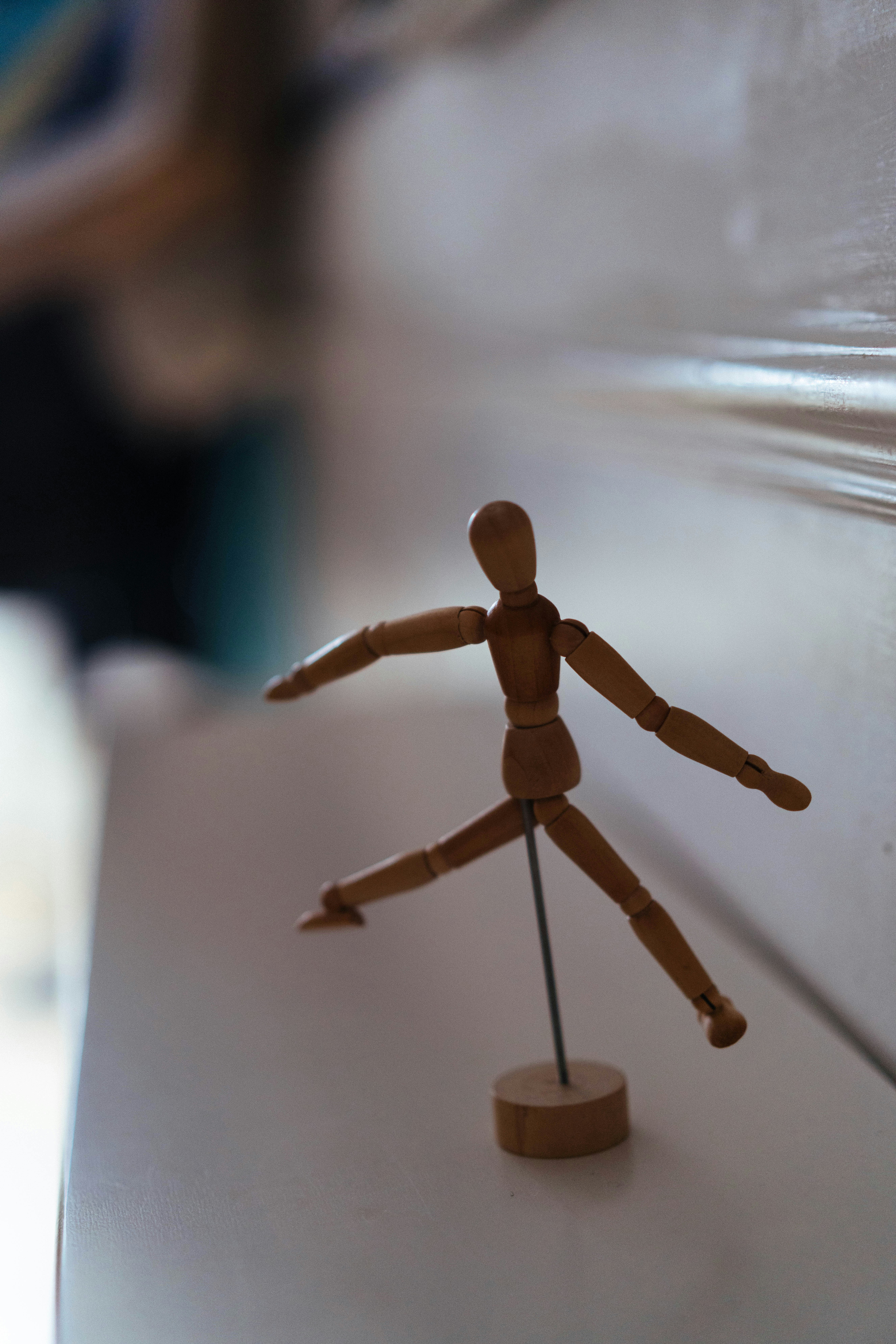 A wooden artist mannequin posed in a dynamic leap on a white surface