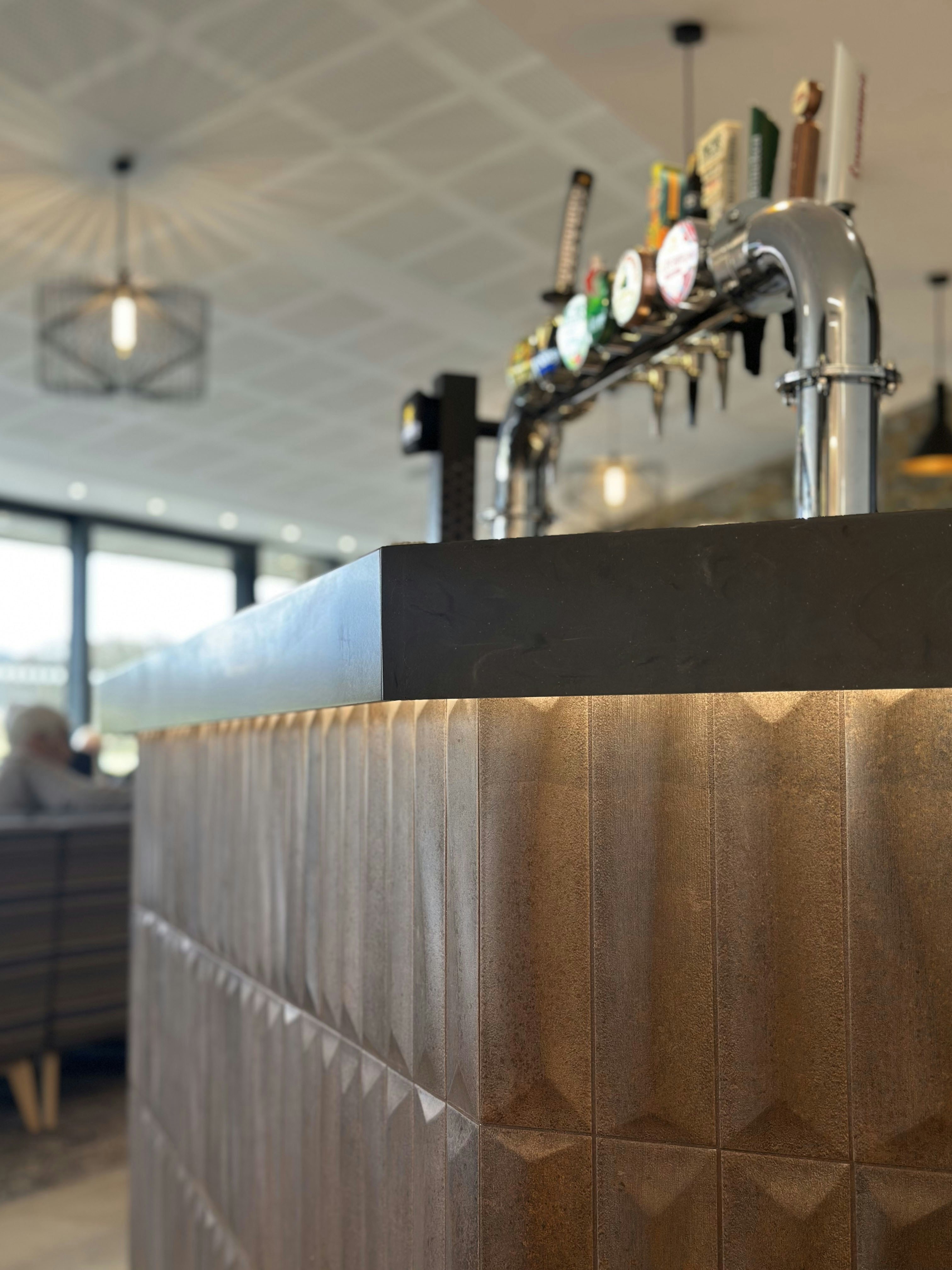 A textured bronze bar counter with beer taps in a modern pub