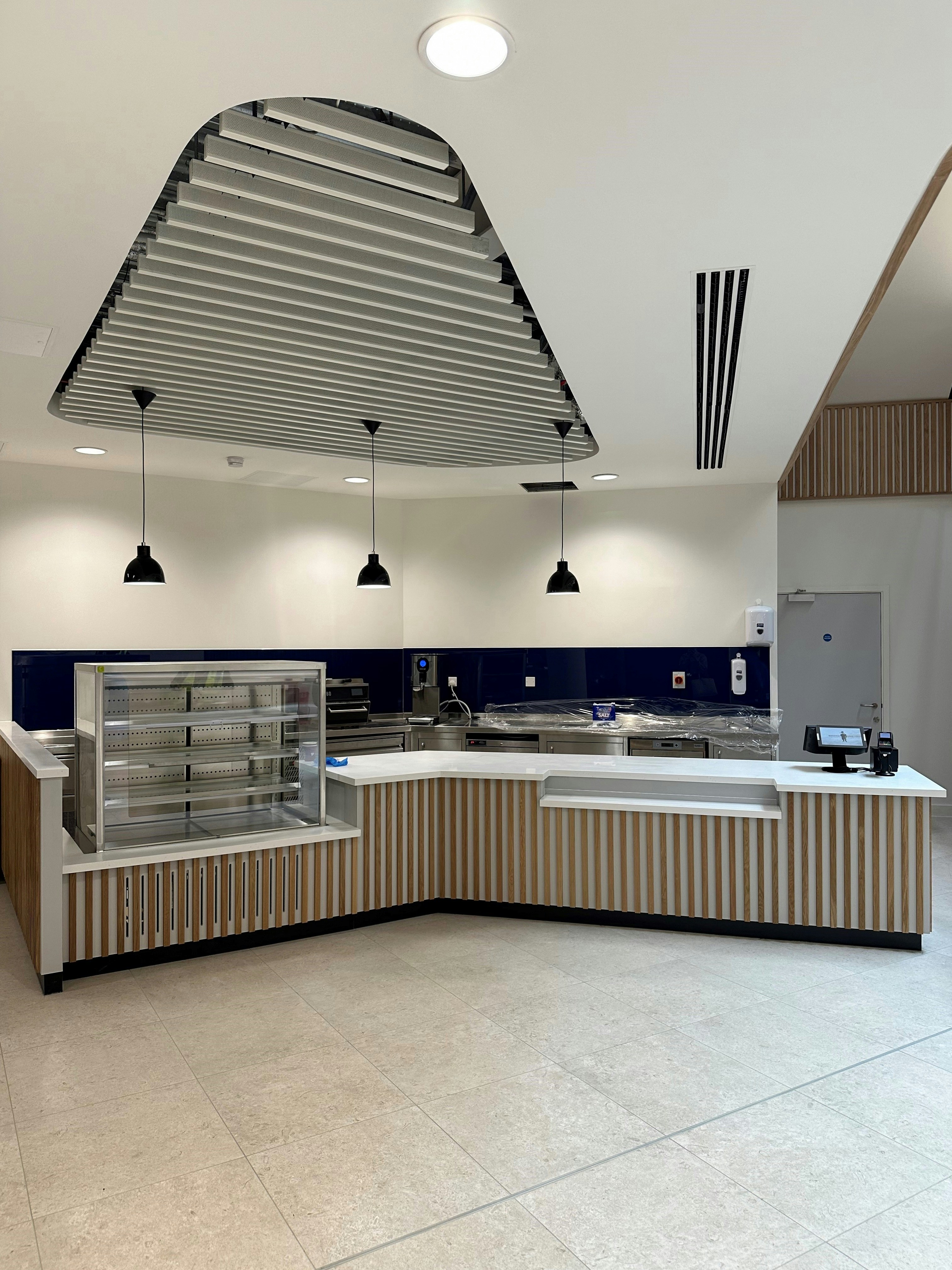 A modern cafe counter with wooden slats and a glass display case