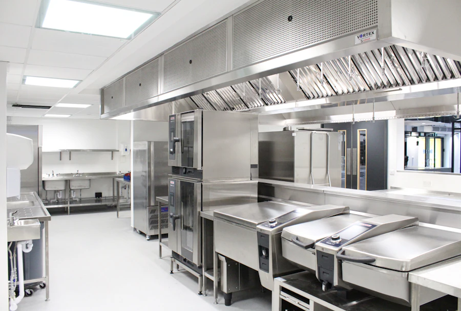 A commercial kitchen with stainless steel benches and an extraction hood