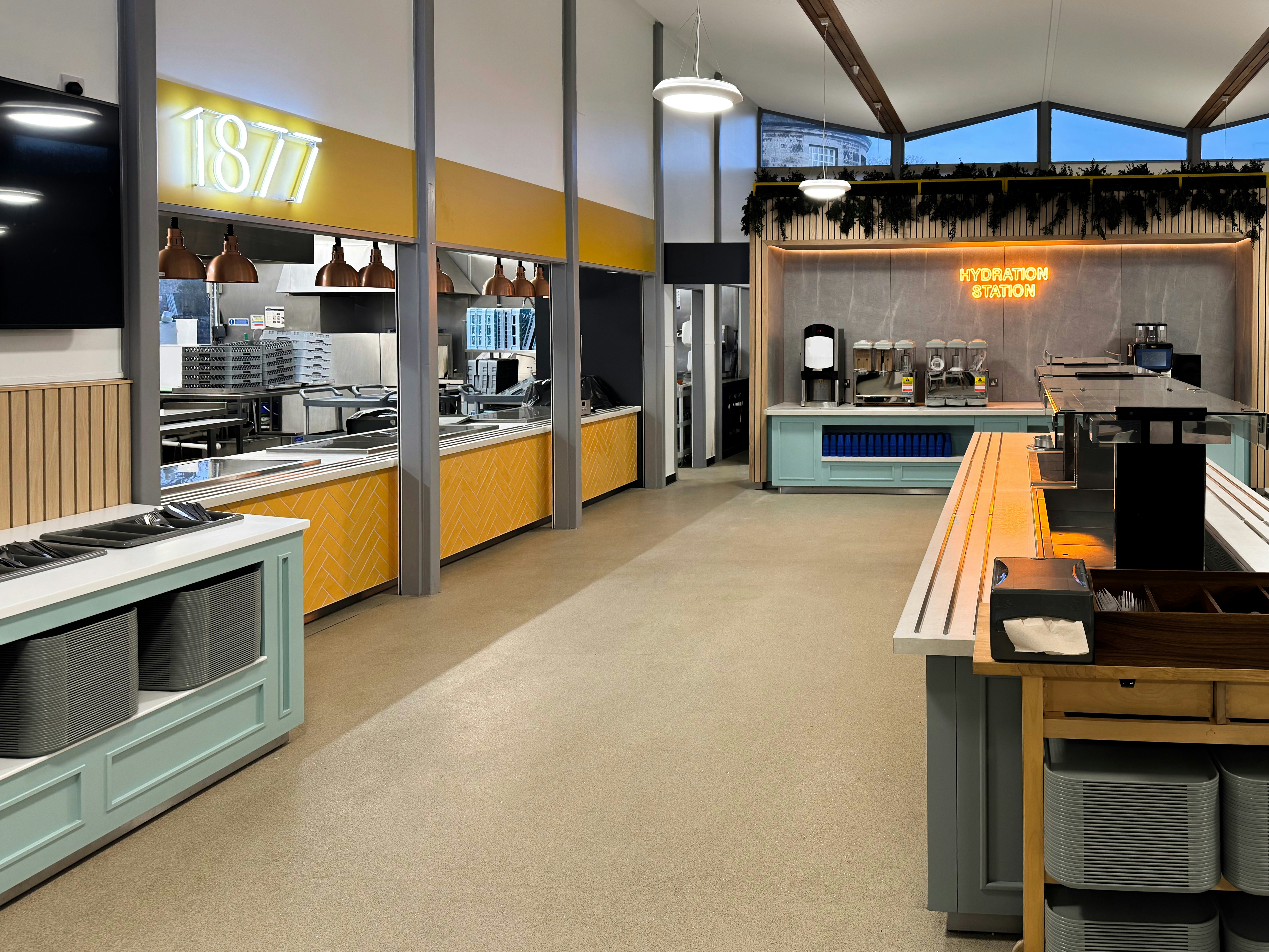 A modern cafeteria with a yellow kitchen area and a hydration station sign