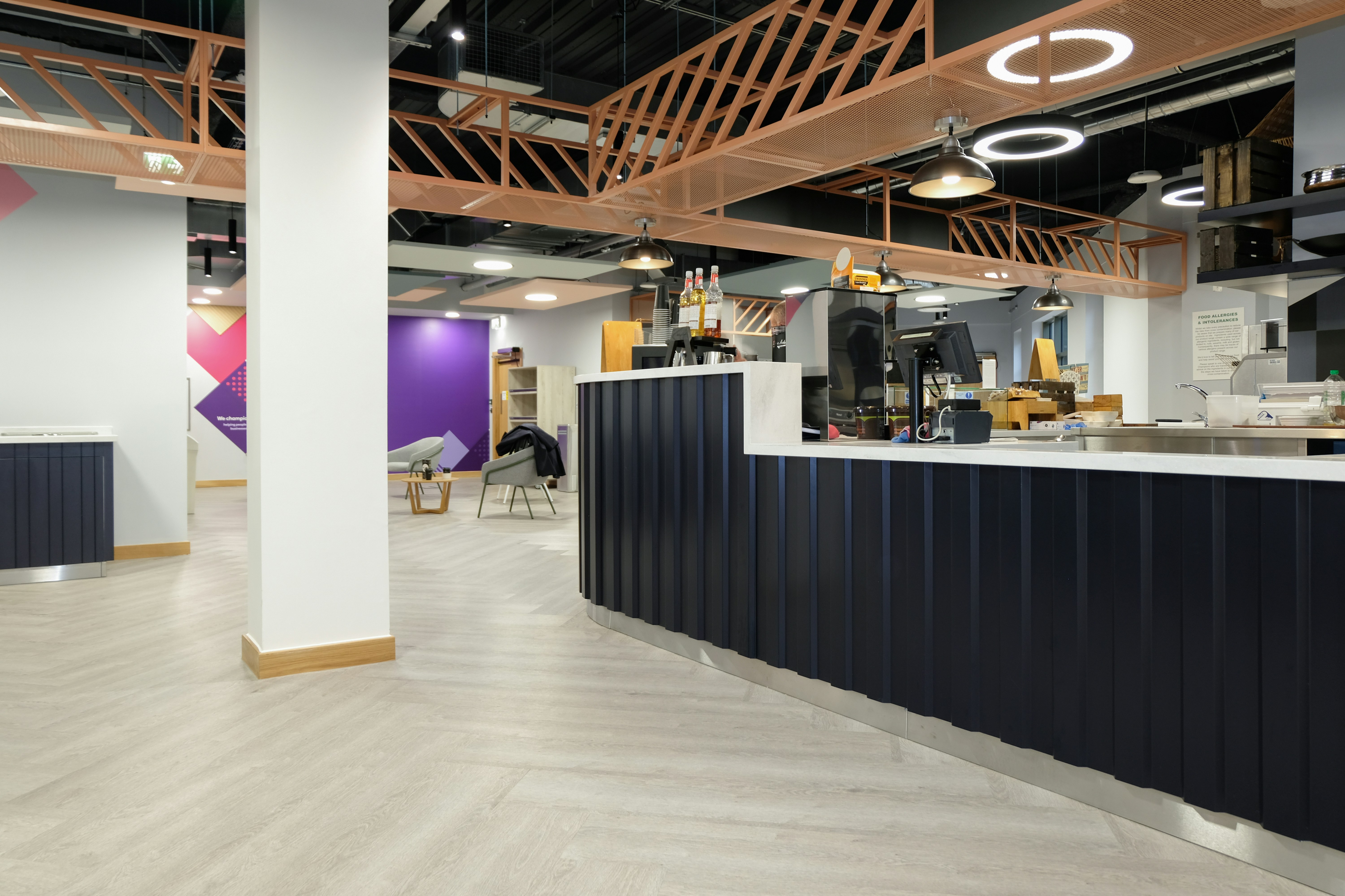 A modern cafe interior with a dark blue counter and light wood flooring