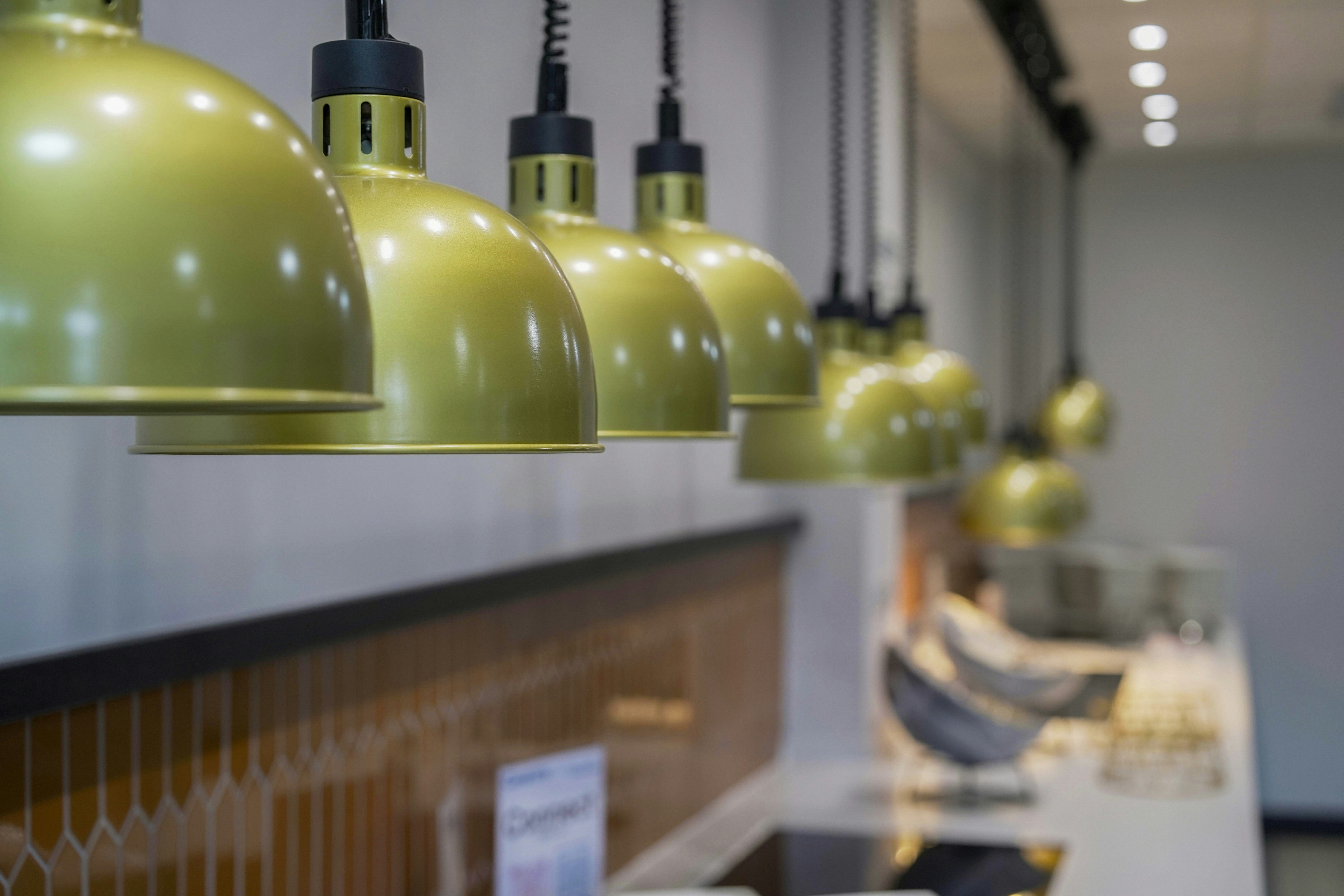 A row of gold pendant lights hanging above a modern kitchen counter