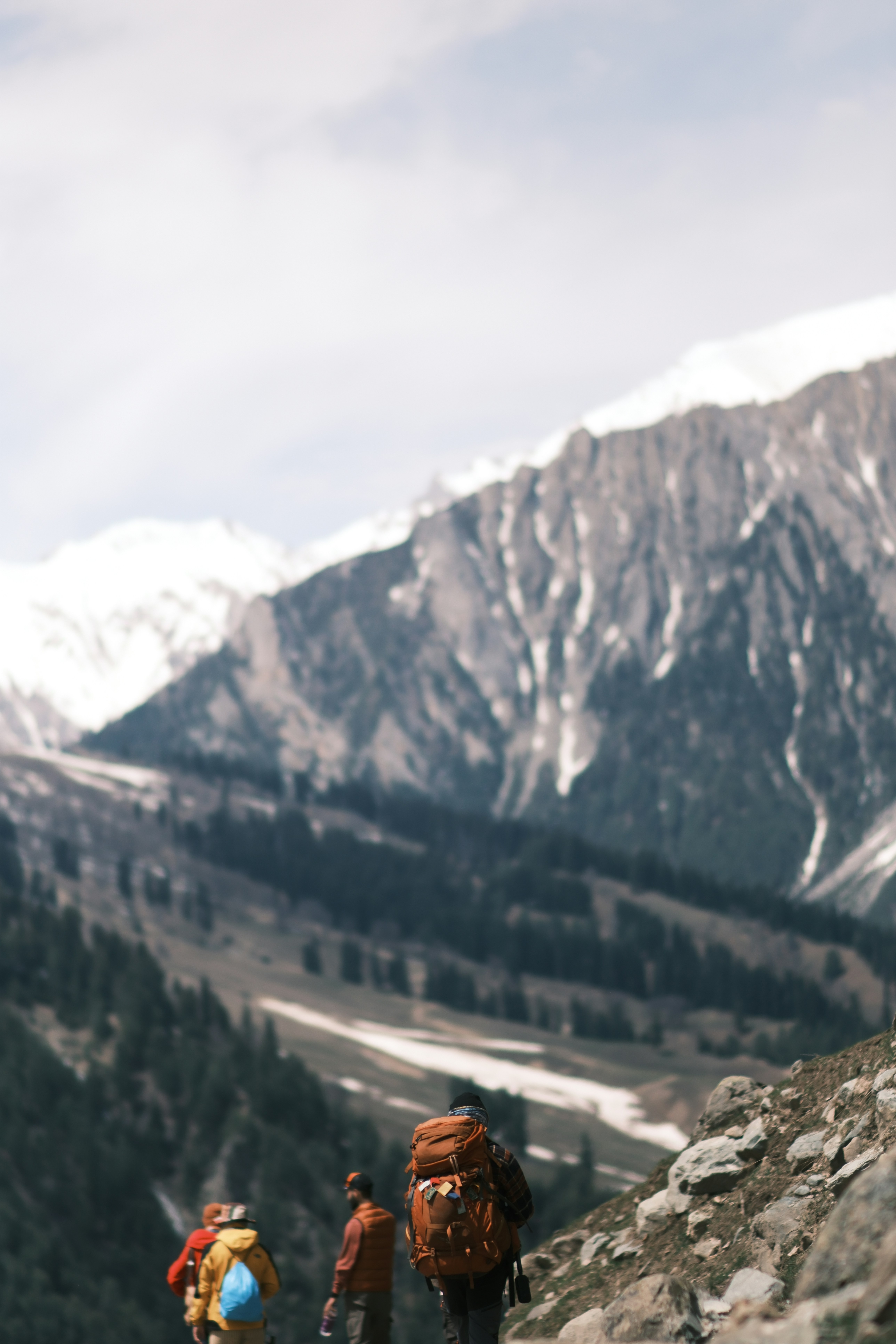 Three hikers with backpacks walking on a rocky mountain trail
