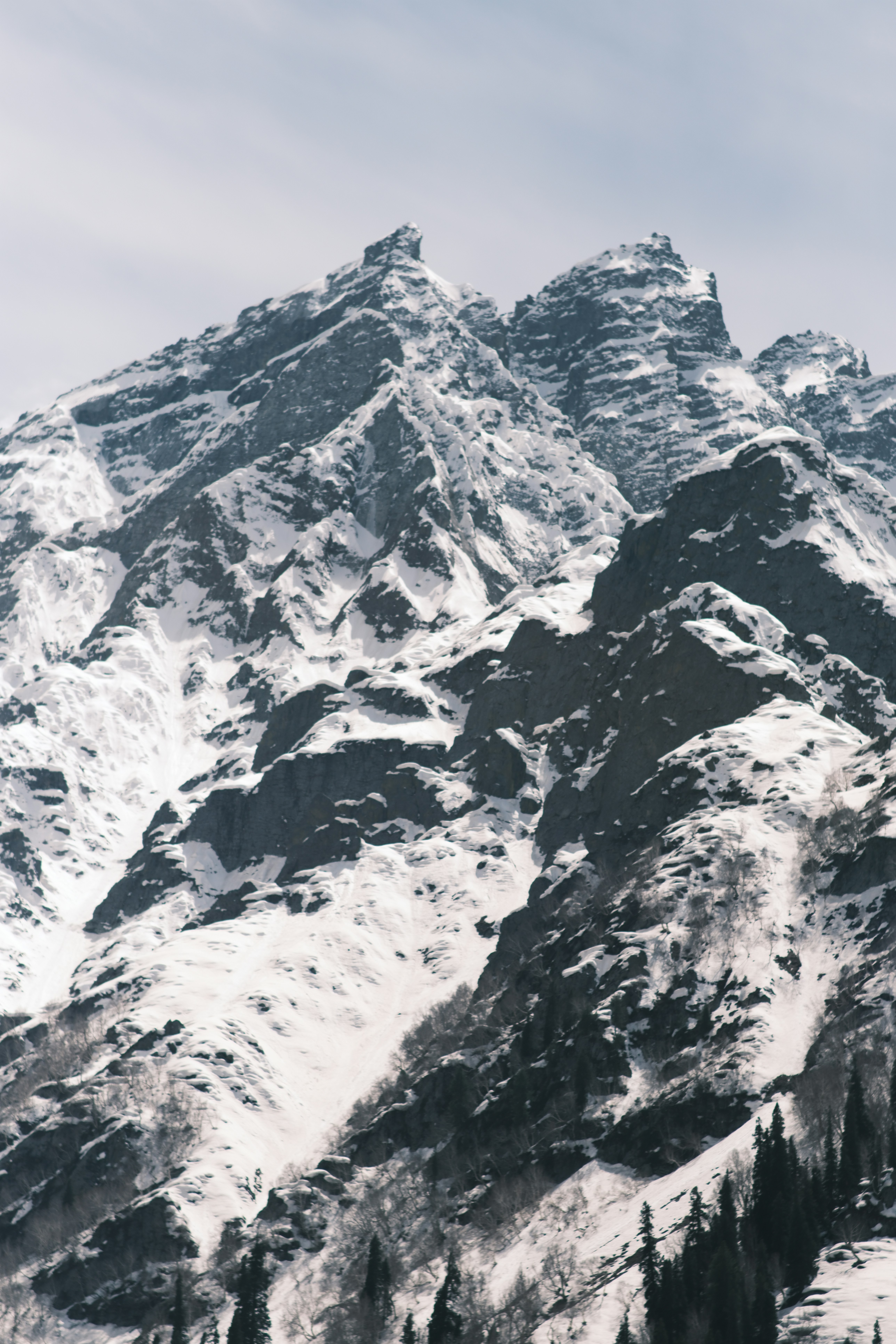 A steep mountain peak covered in snow and dark rock faces