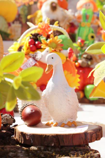 A white duck figurine and an acorn on a wooden slice with autumn decor