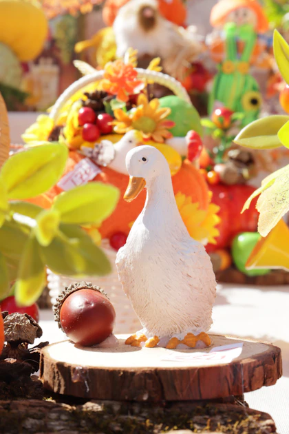 A white duck figurine and an acorn on a wooden slice with autumn decor