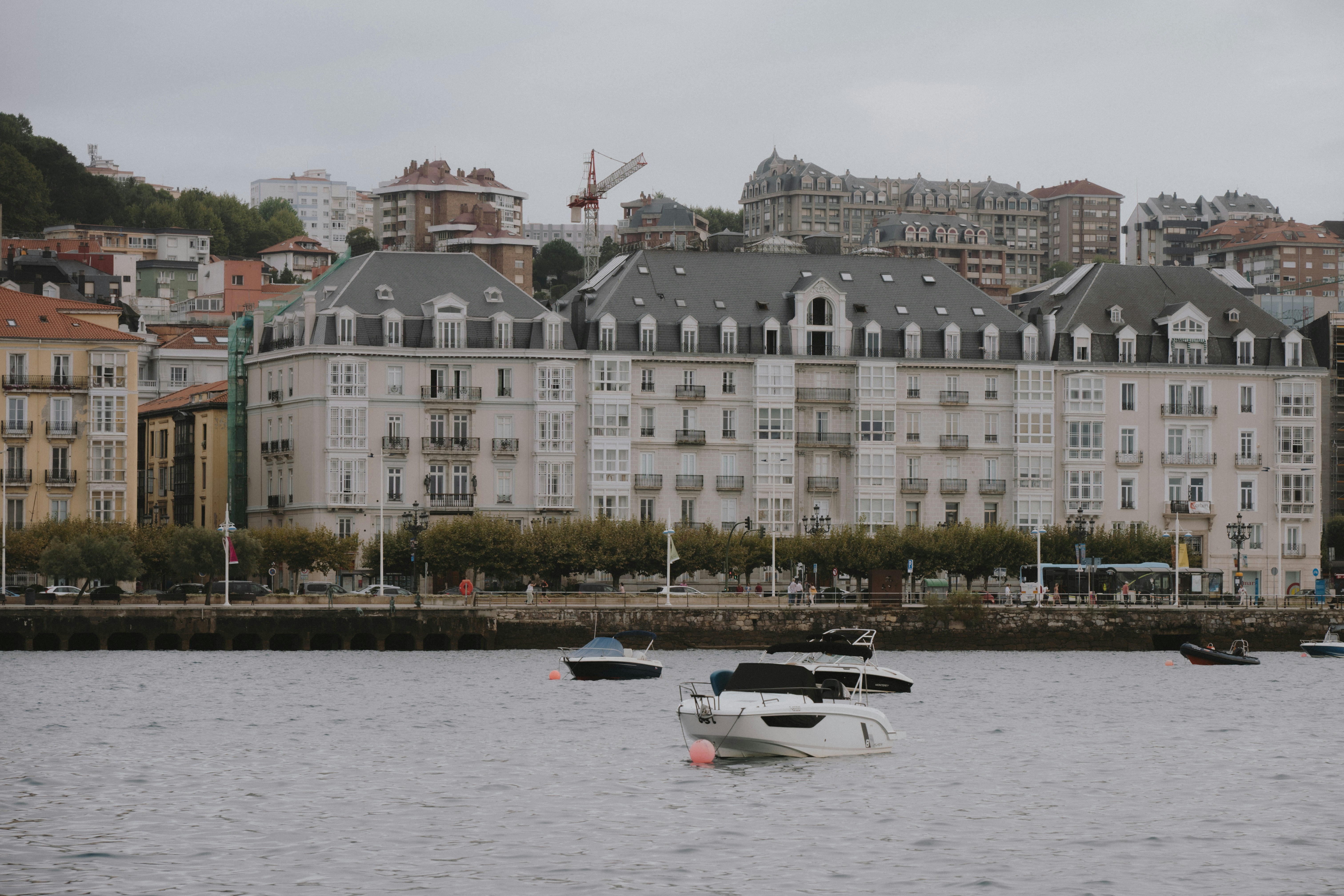 Boats moored on a river in front of a row of apartment buildings