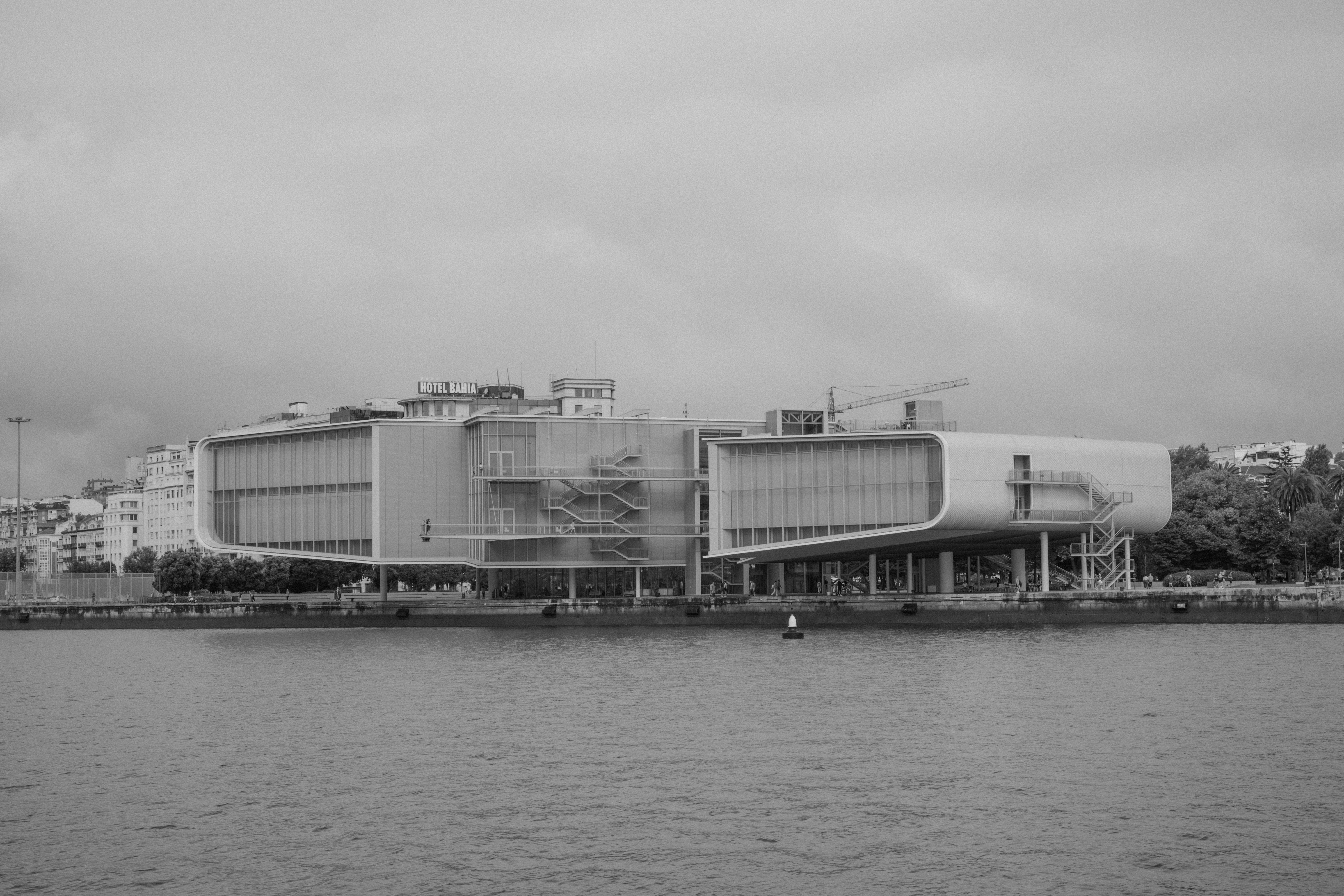 Modern building with glass facade and external staircases on a riverbank