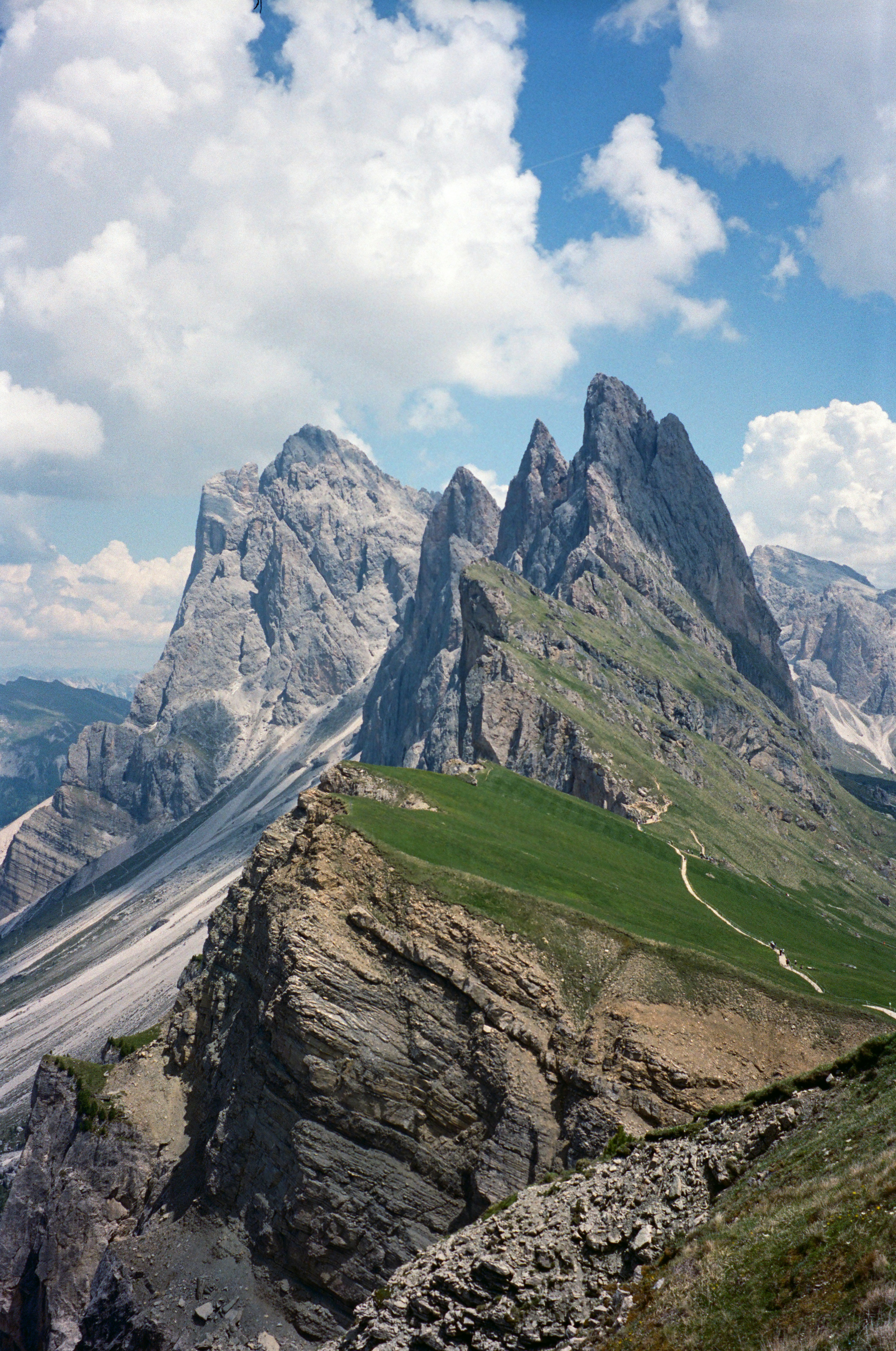 Jagged limestone peaks of Seceda in the Dolomites under a blue sky with clouds
