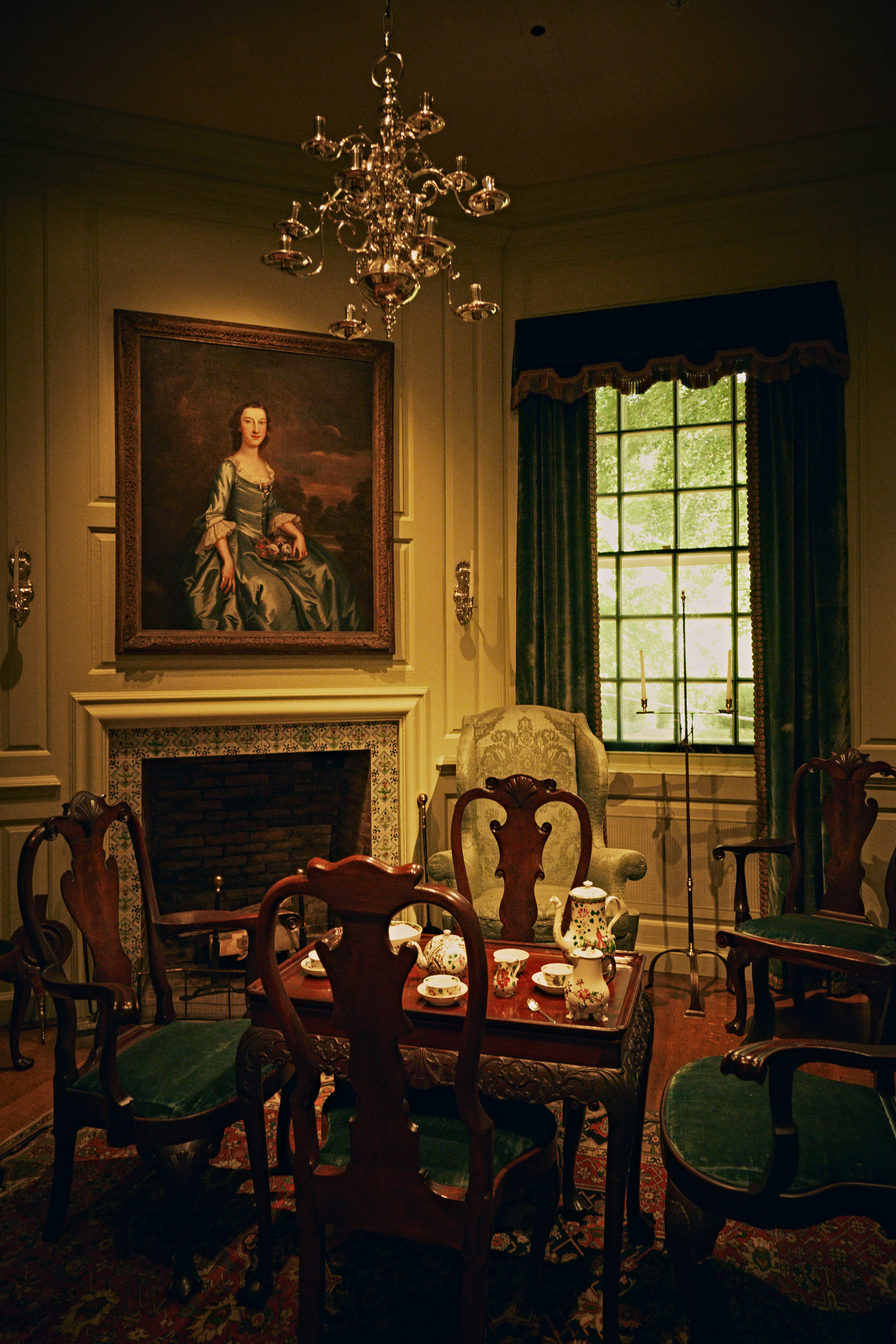 A tea set on a wooden table surrounded by chairs in a historic room