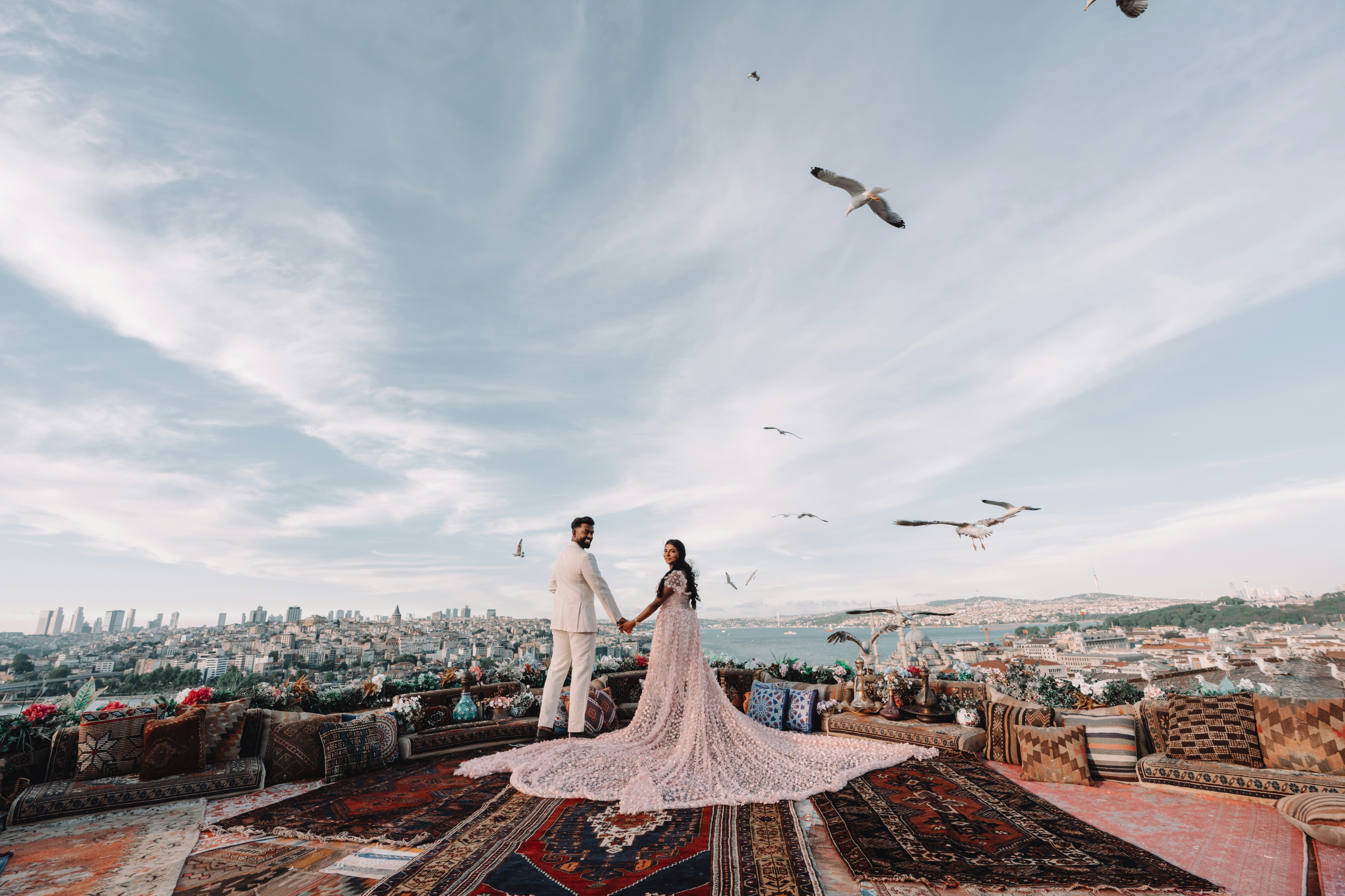 A couple holding hands on a rooftop terrace overlooking the Istanbul skyline