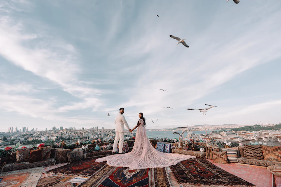 Bride and groom on a carpeted rooftop under seagulls, looking at the Istanbul skyline