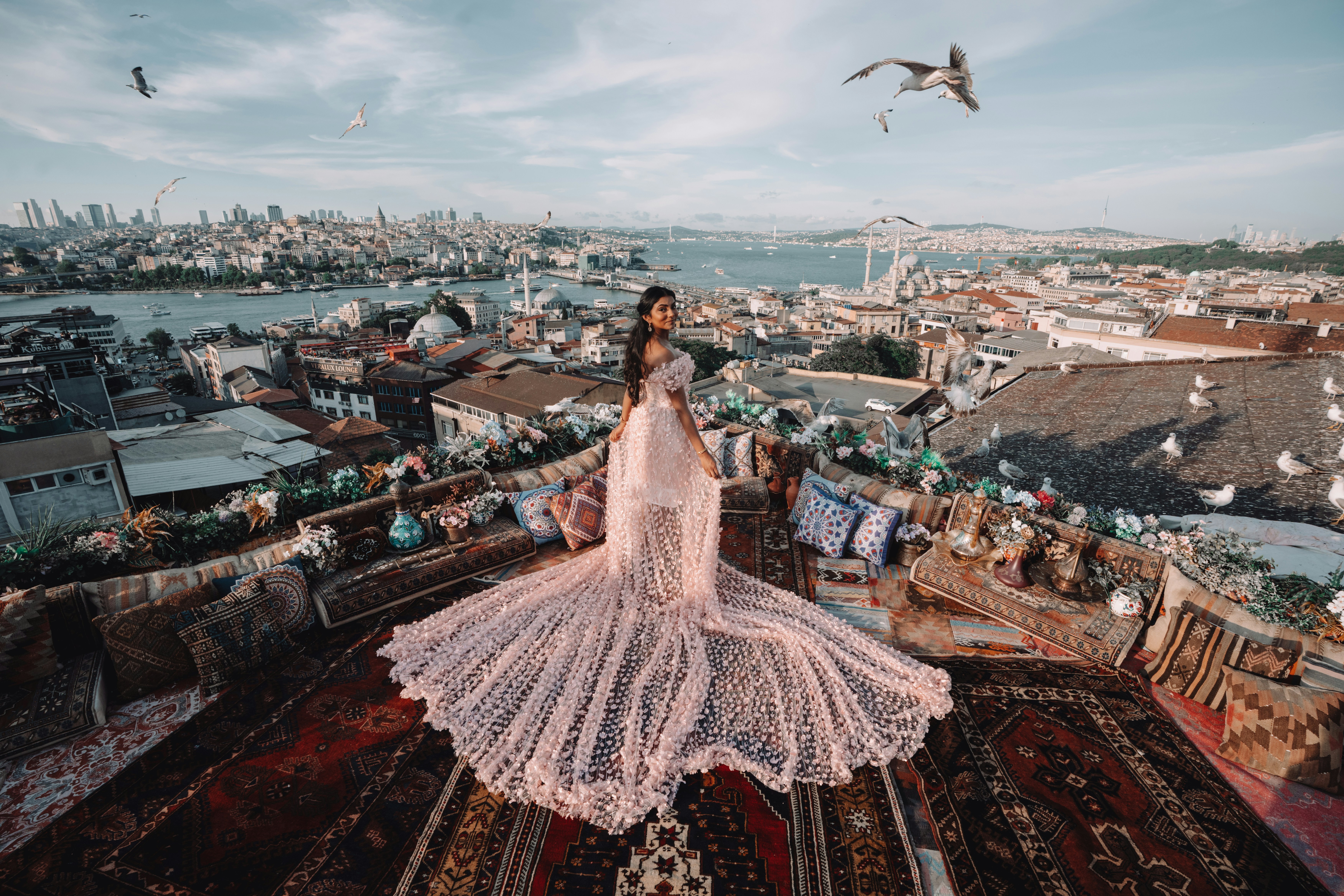 A woman in a long pink floral dress on a rooftop terrace in Istanbul