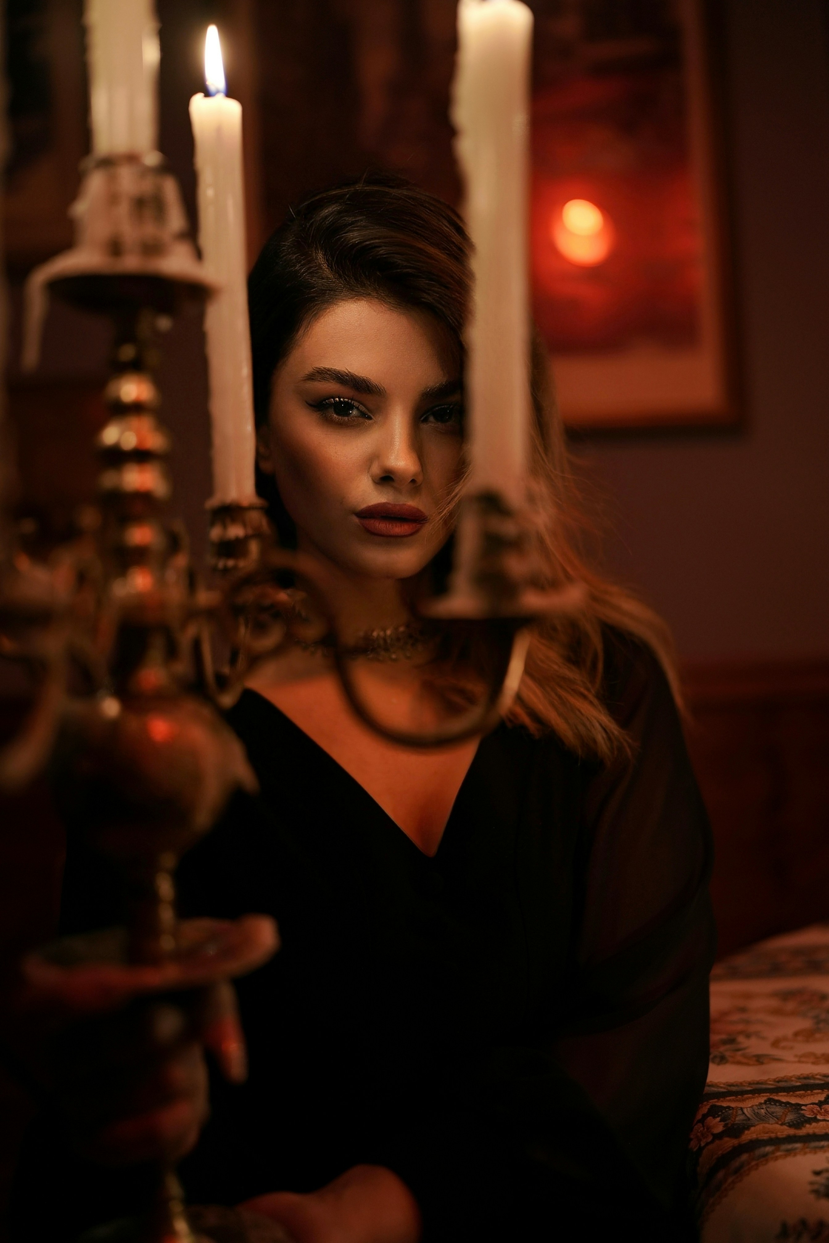 A woman in a black top behind a lit candelabra in a dim room