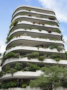 A modern residential building with curved white balconies overflowing with lush green plants