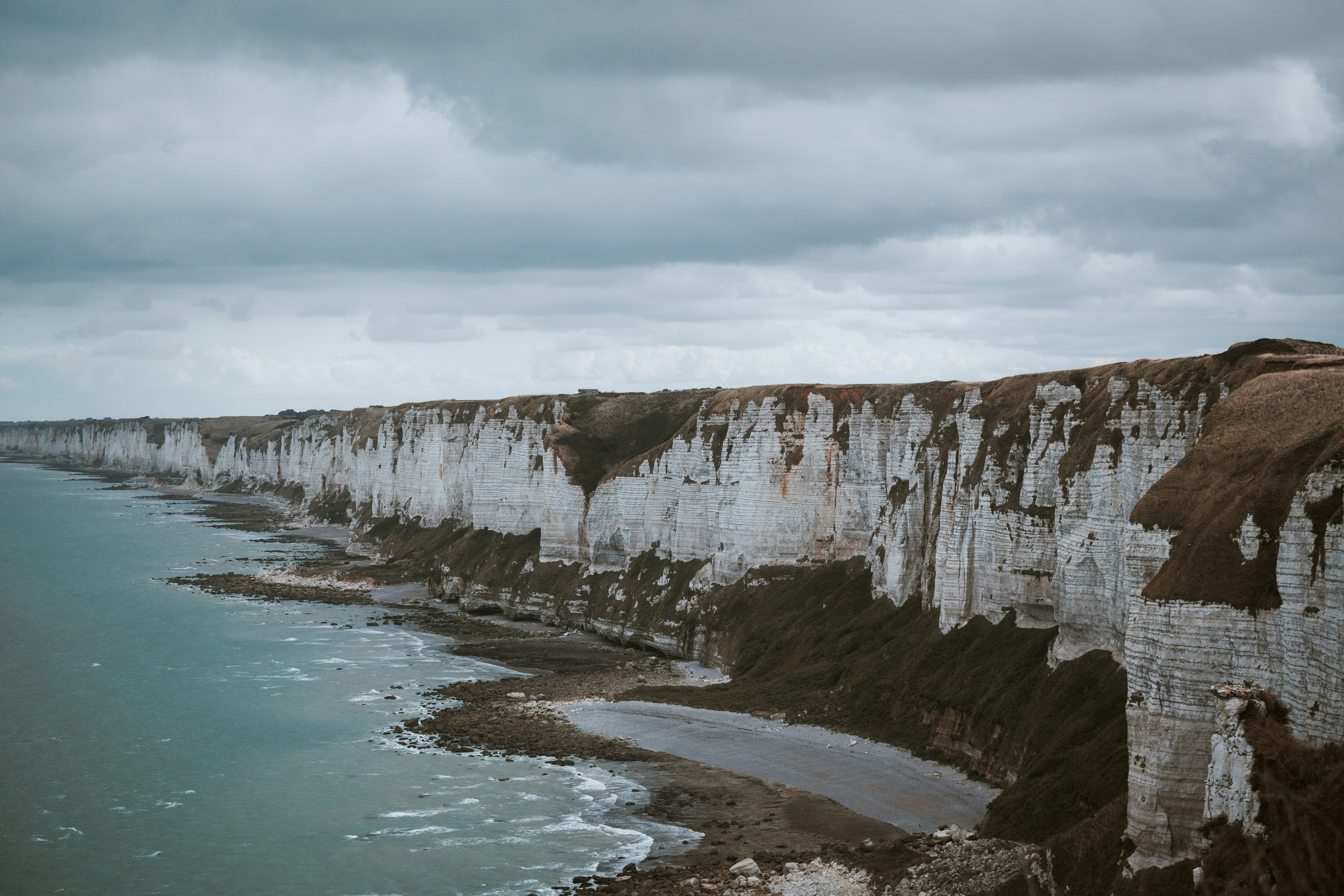 White chalk cliffs rising above a rocky beach and the sea under cloudy skies
