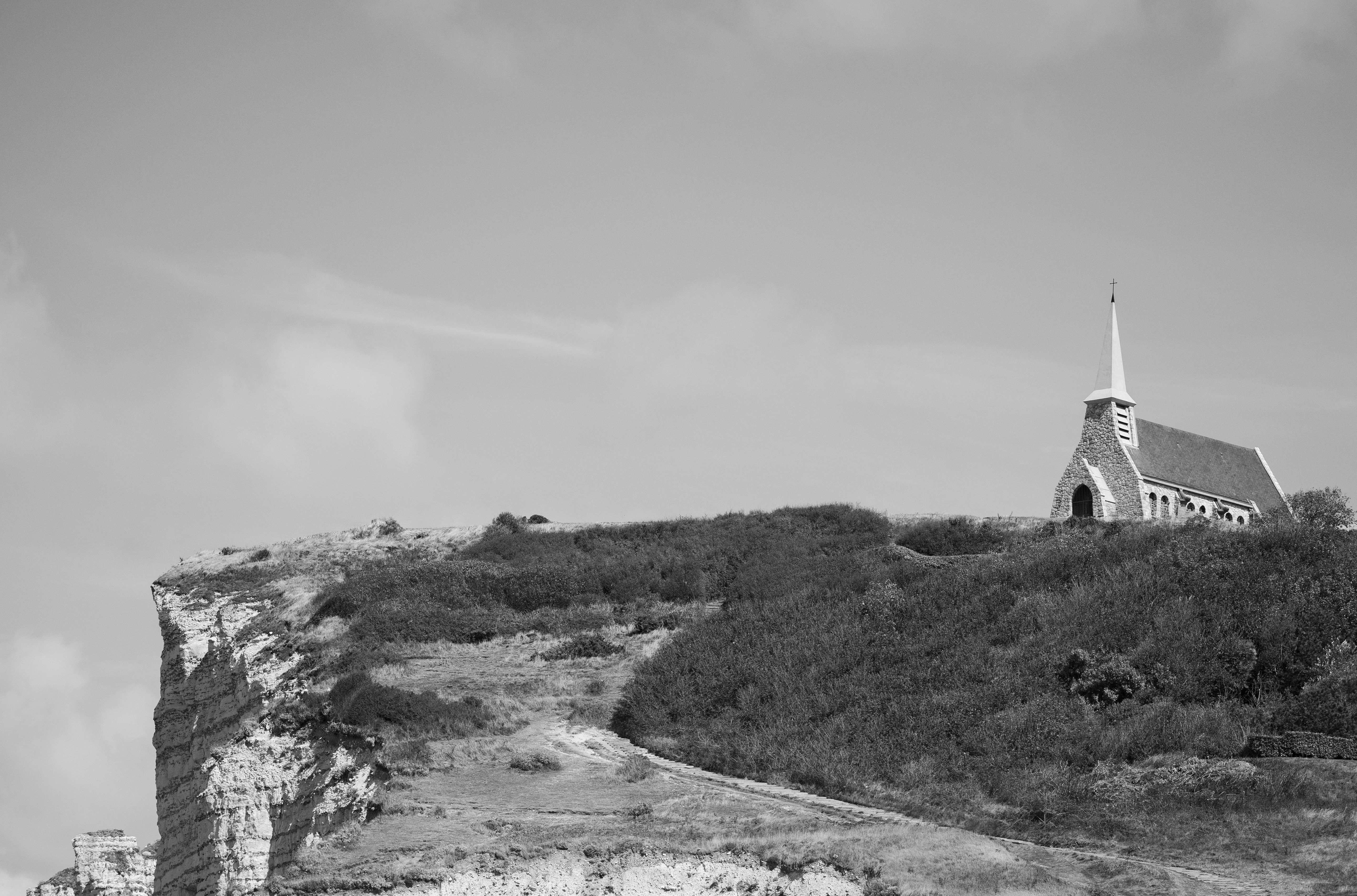 A stone church on a grassy cliff edge above a white chalk coastline