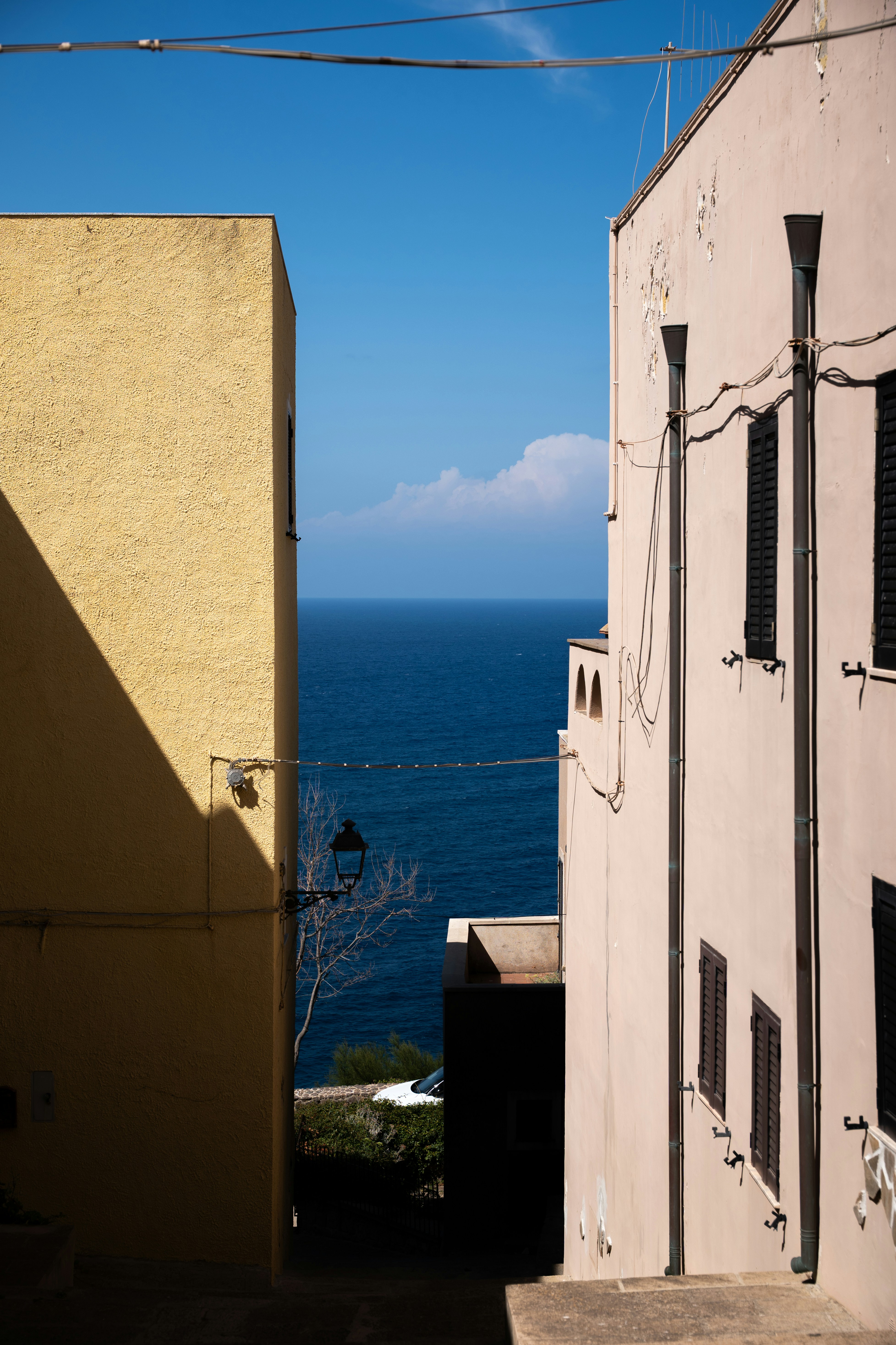 A view of the blue sea between a yellow building and a beige building