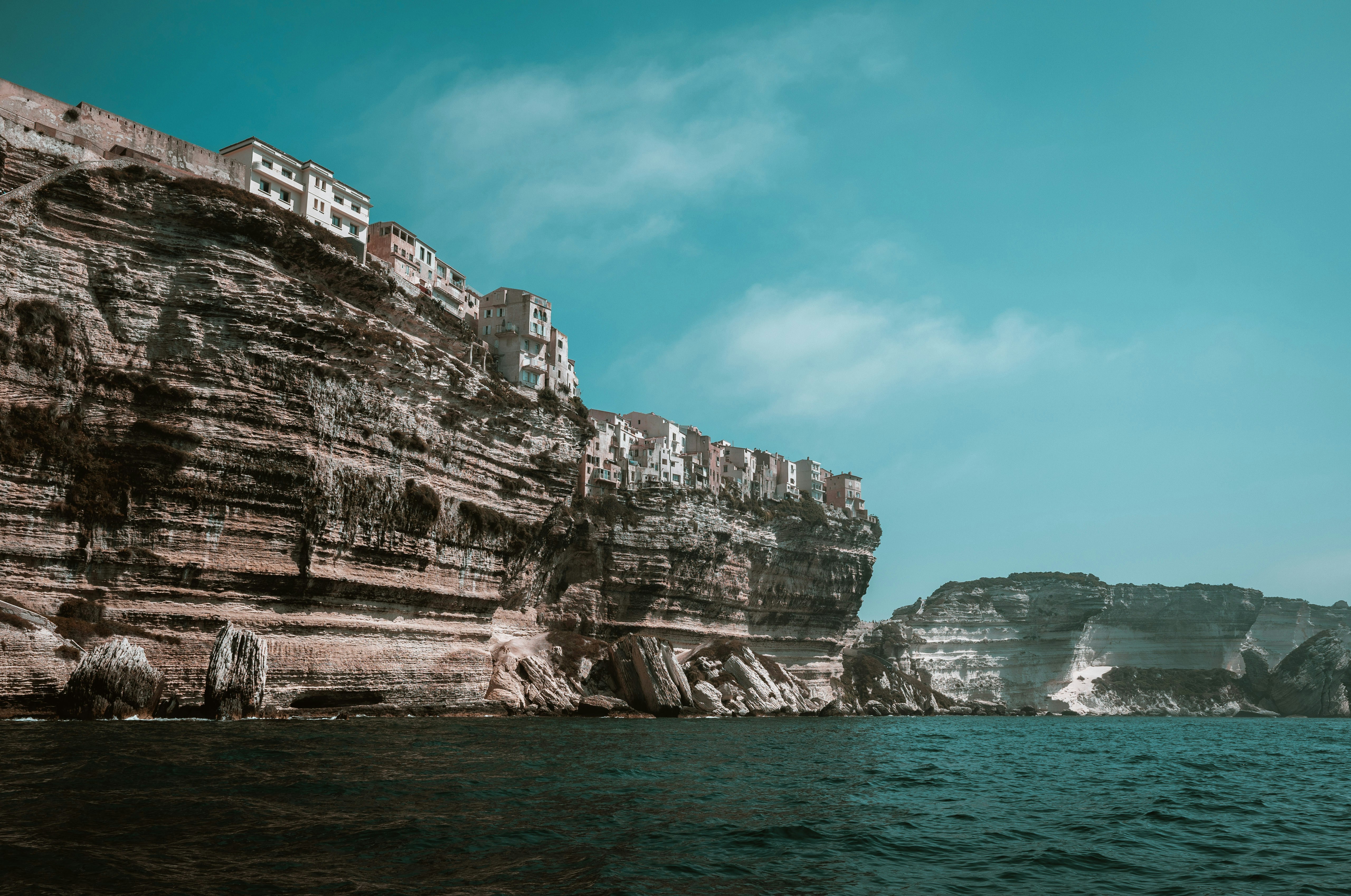 Buildings perched on a high limestone cliff above the blue Mediterranean sea
