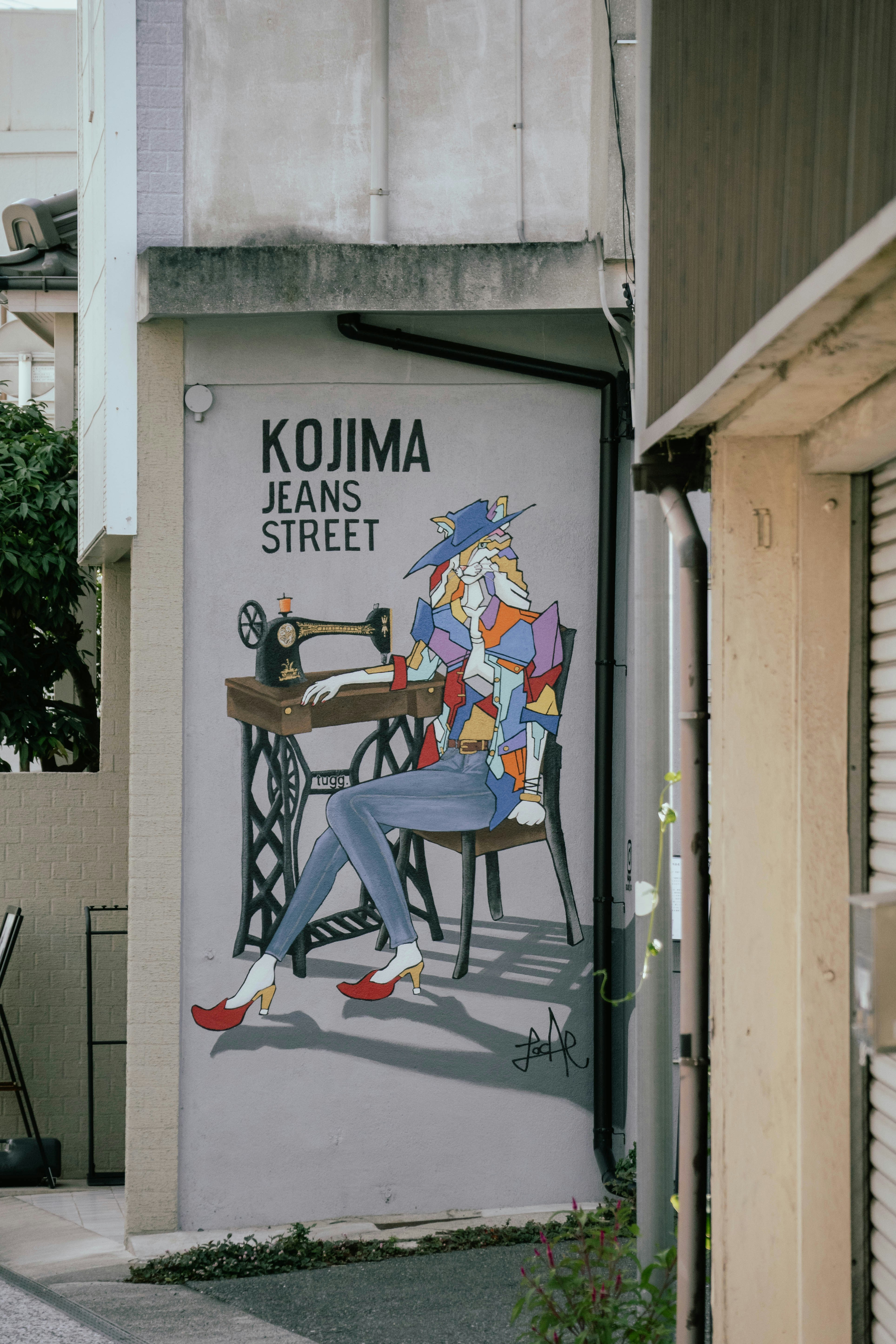 A mural of a person sewing at a machine on a grey wall