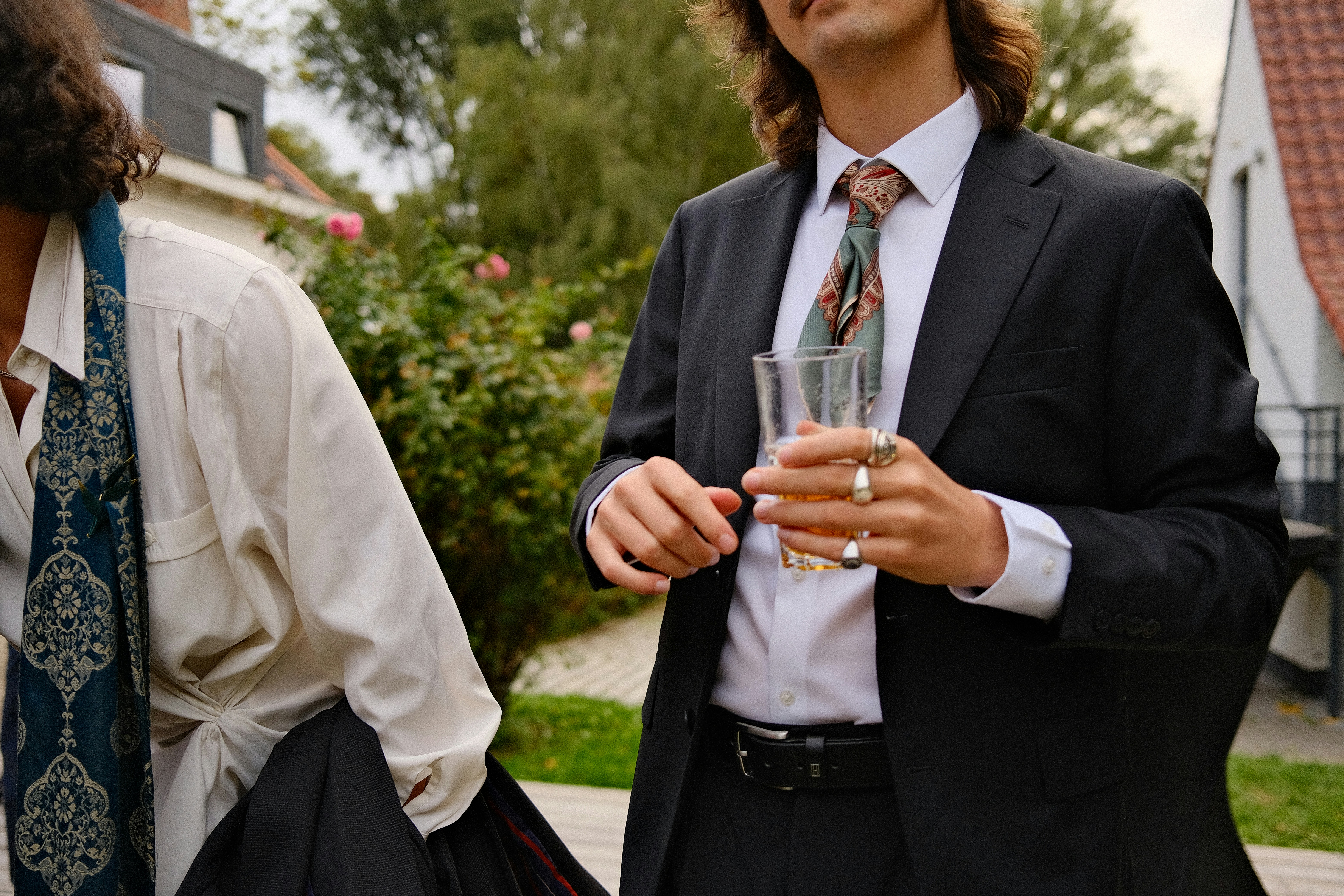 Two people in formal attire with patterned scarves in a garden setting
