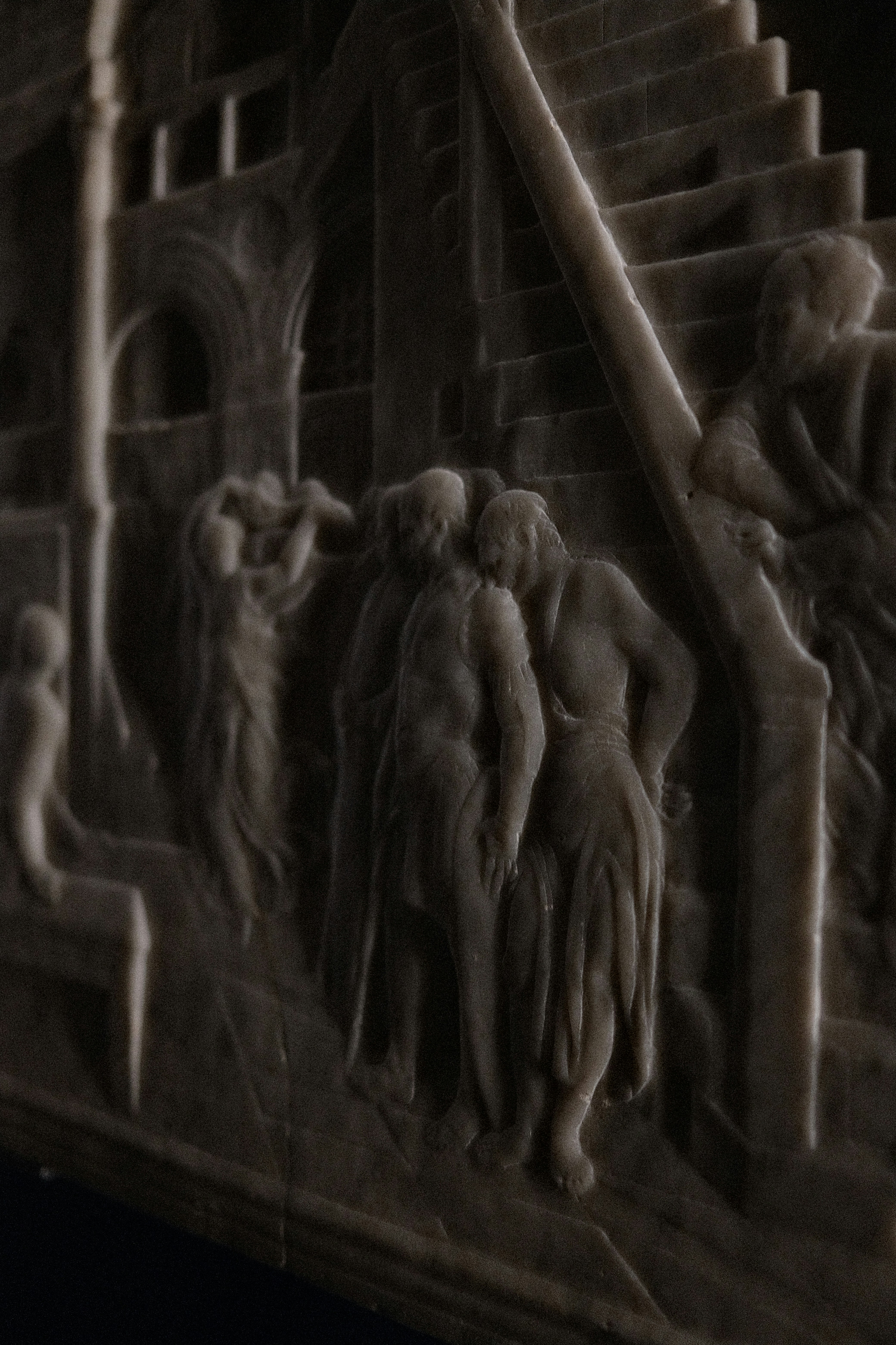 A stone relief carving of figures on stairs in a dimly lit room