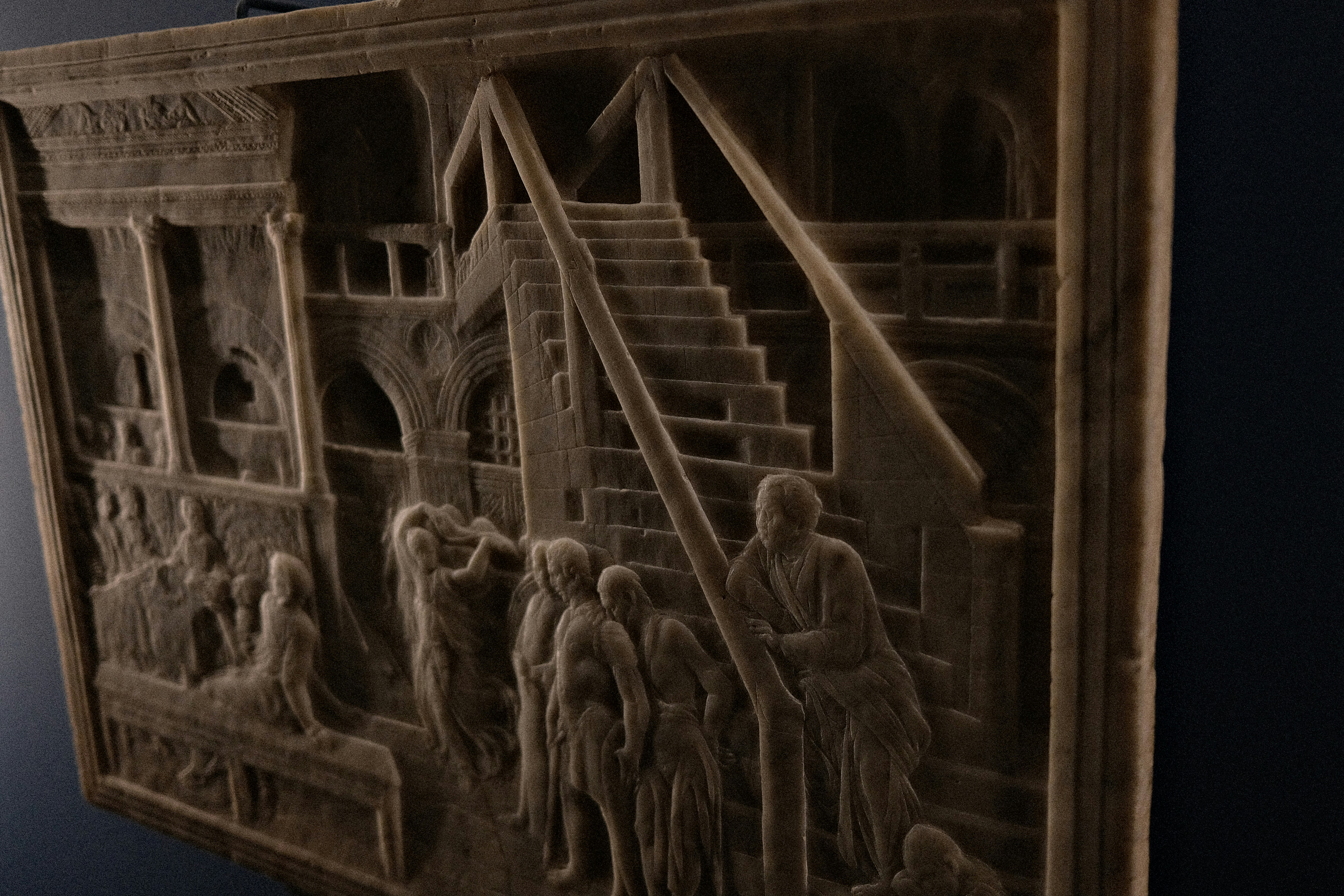 A stone relief carving depicting people on stairs and in an arched building