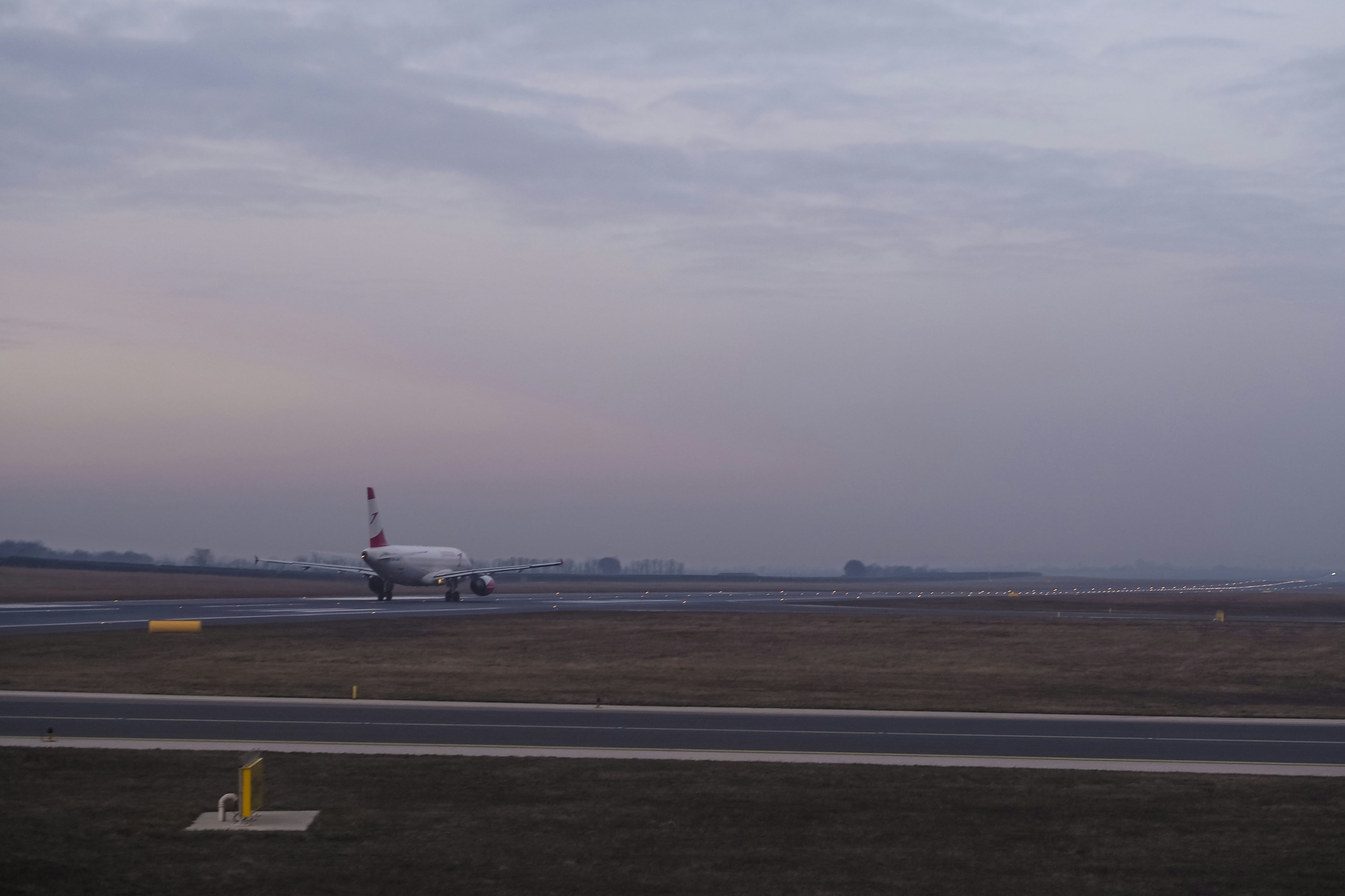 A passenger airplane taxiing on an airport runway under a soft grey sky