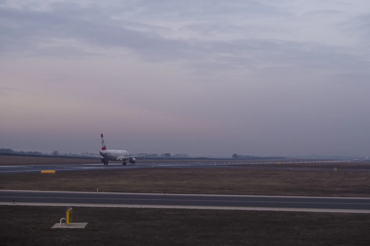 A passenger airplane taxiing on an airport runway under a soft grey sky