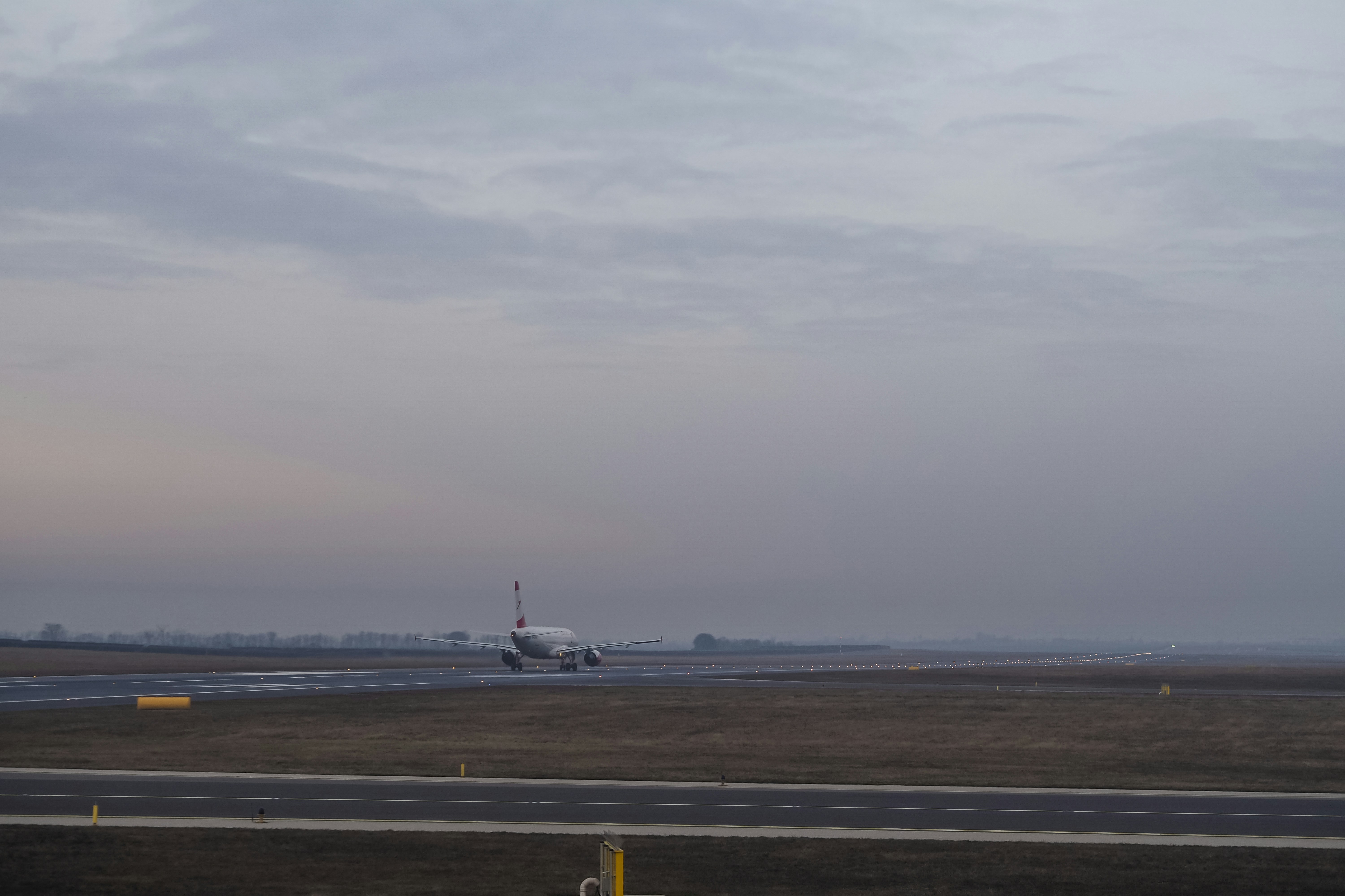 An airplane taxiing on a runway under a cloudy grey sky