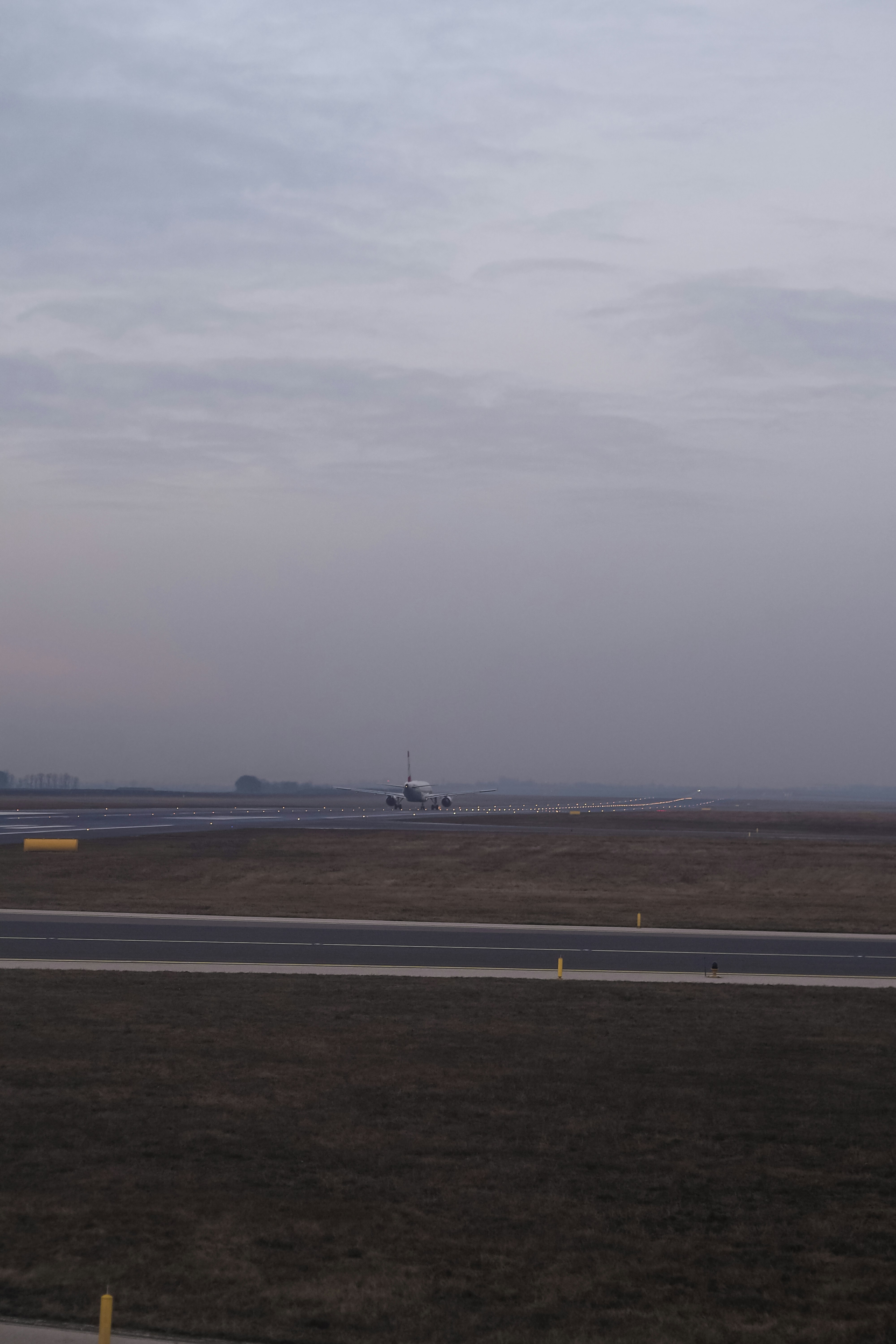 An airplane taxiing on a runway at an airport under a cloudy sky