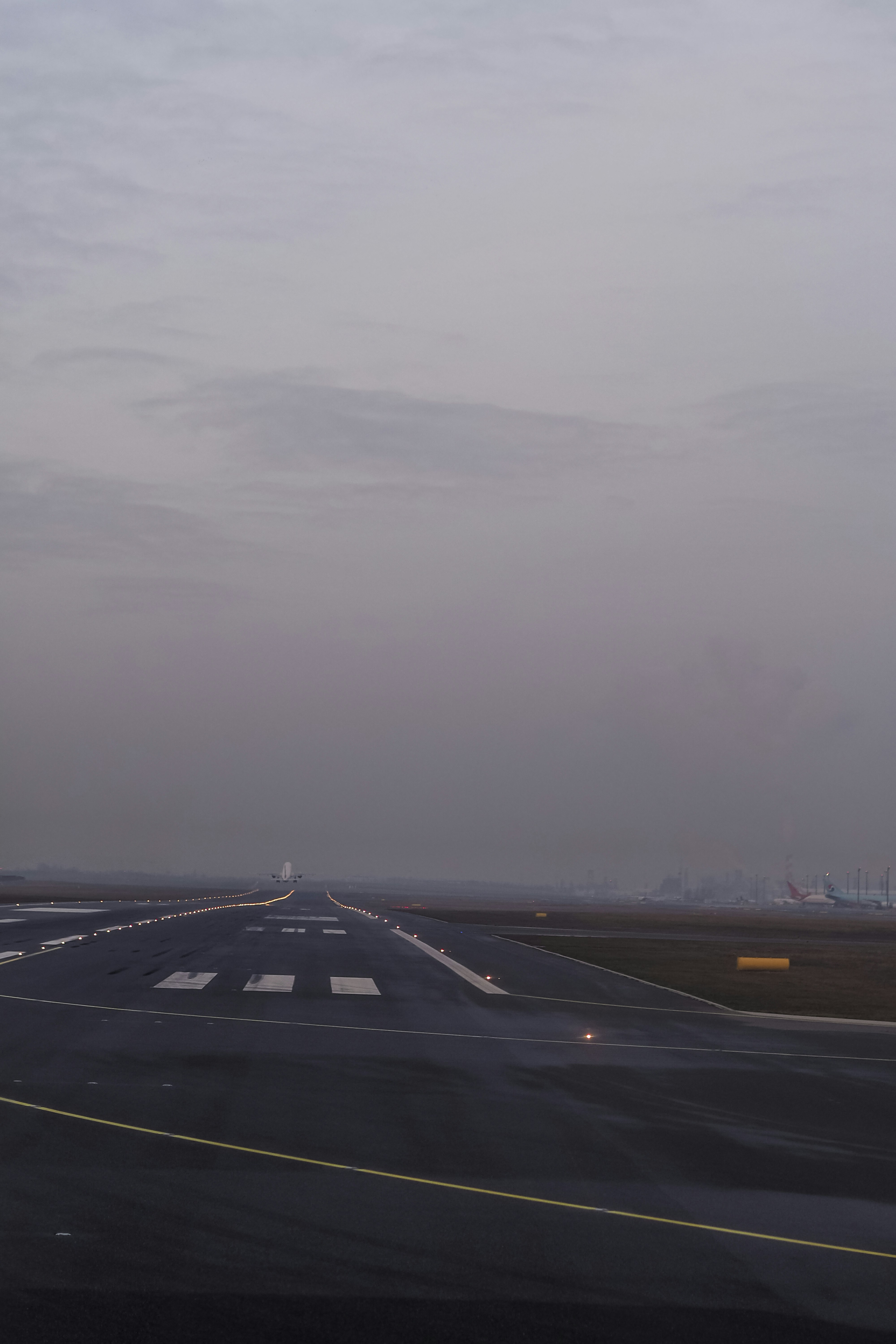 An airplane taking off from a wet airport runway under a grey overcast sky