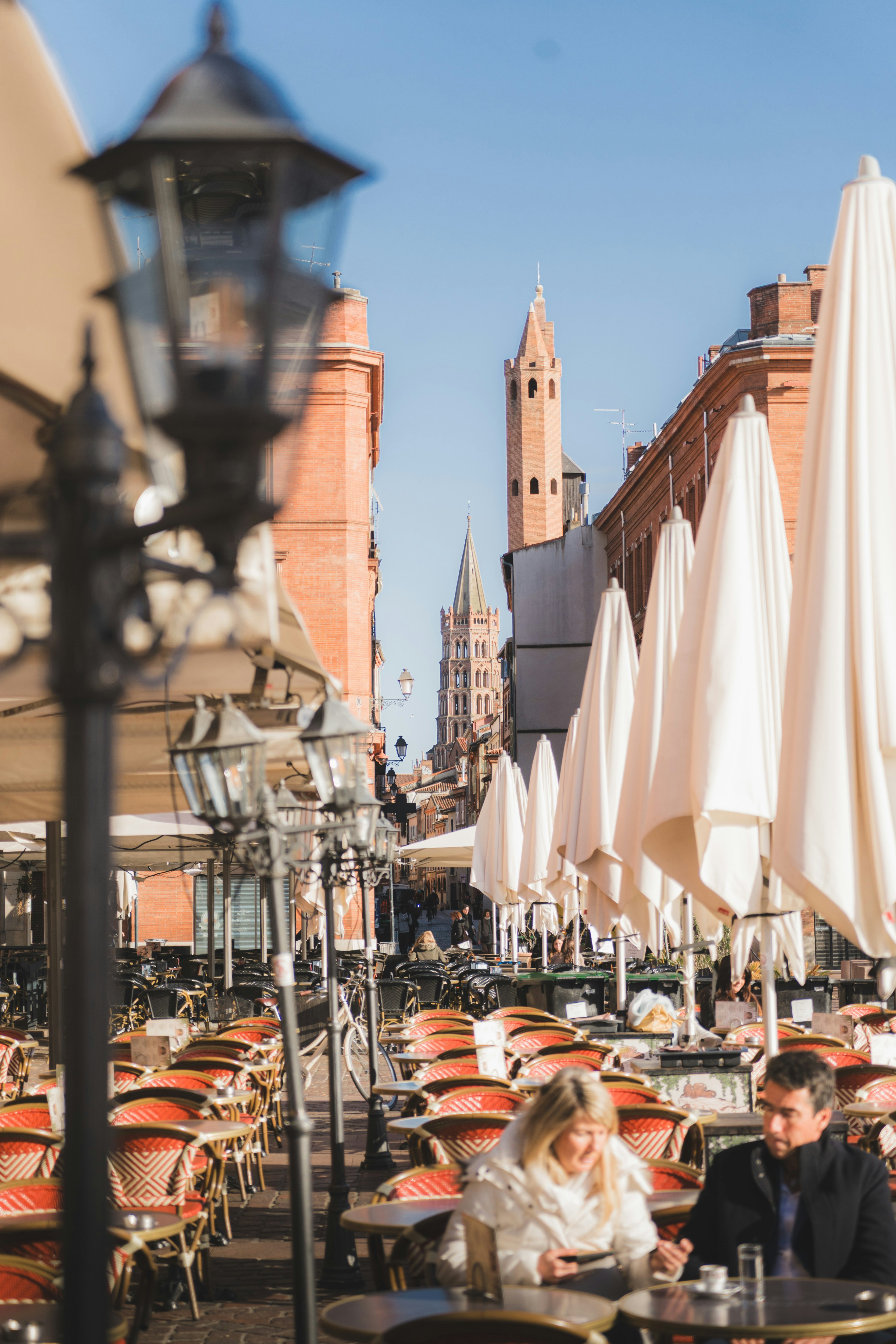 People at outdoor cafe tables with white umbrellas in Toulouse, France