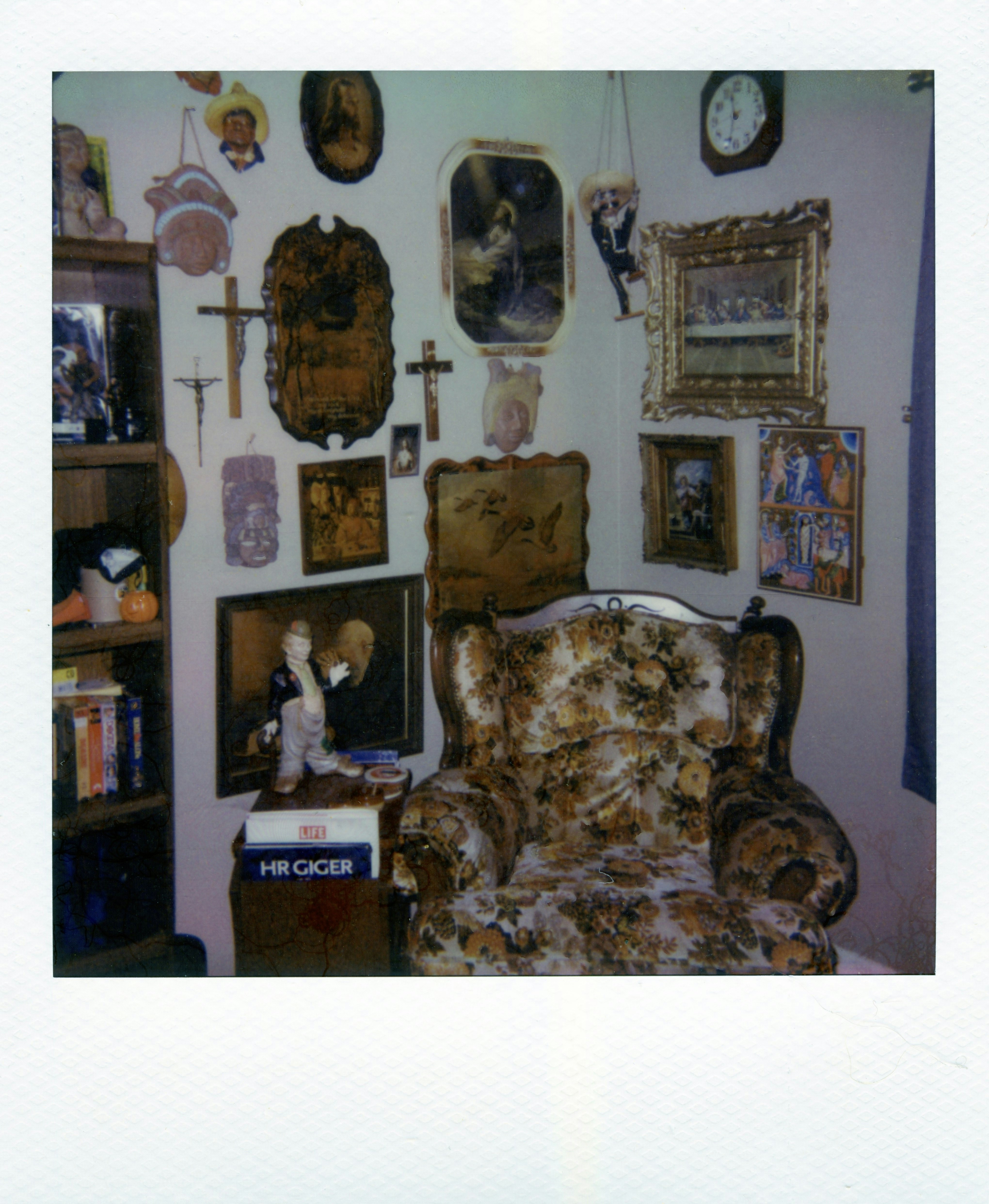 An armchair with floral upholstery surrounded by religious art and wall decor